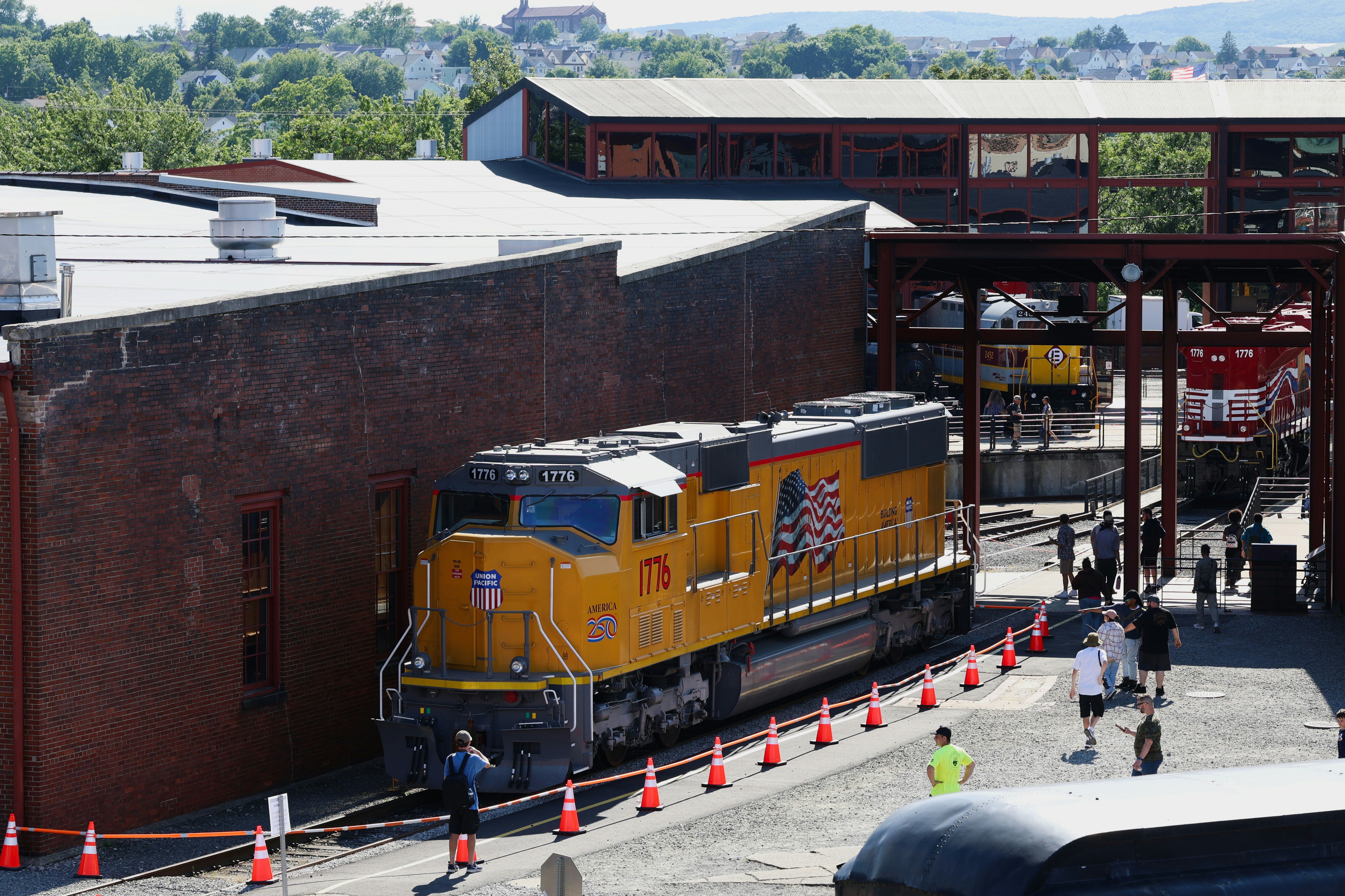 A yellow Union Pacific locomotive parked beside a brick building with people nearby