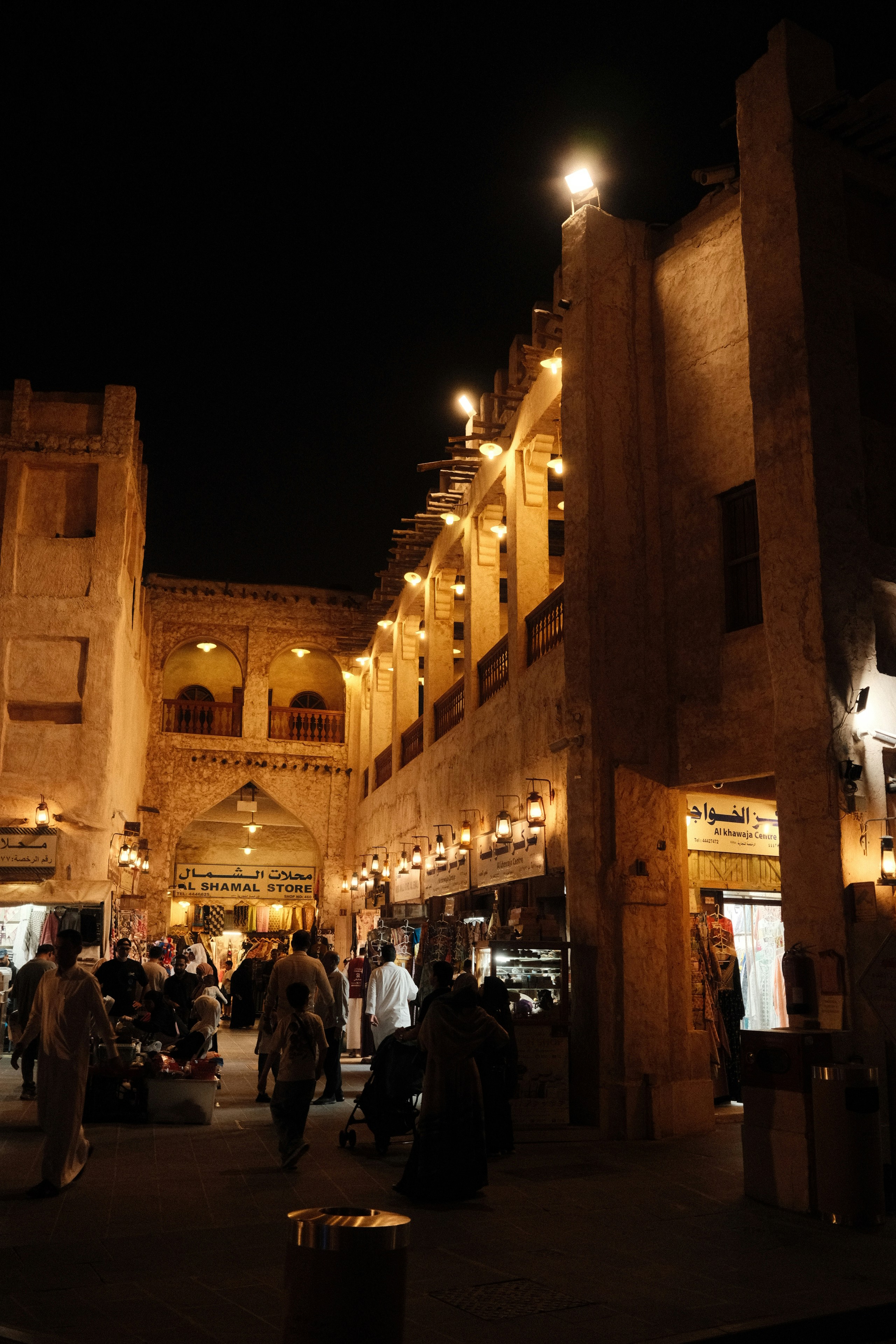 People walking through a traditional market at night with warm lantern lighting