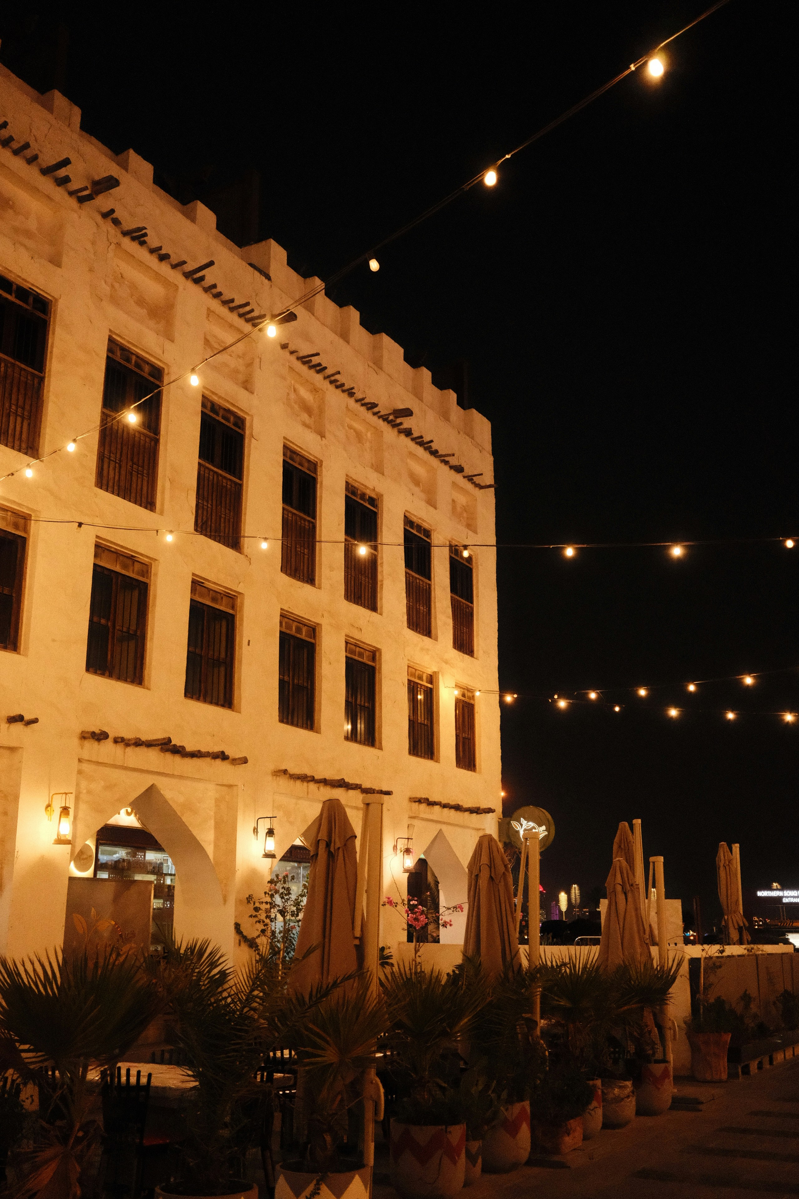 A white building with arched doorways and string lights at night