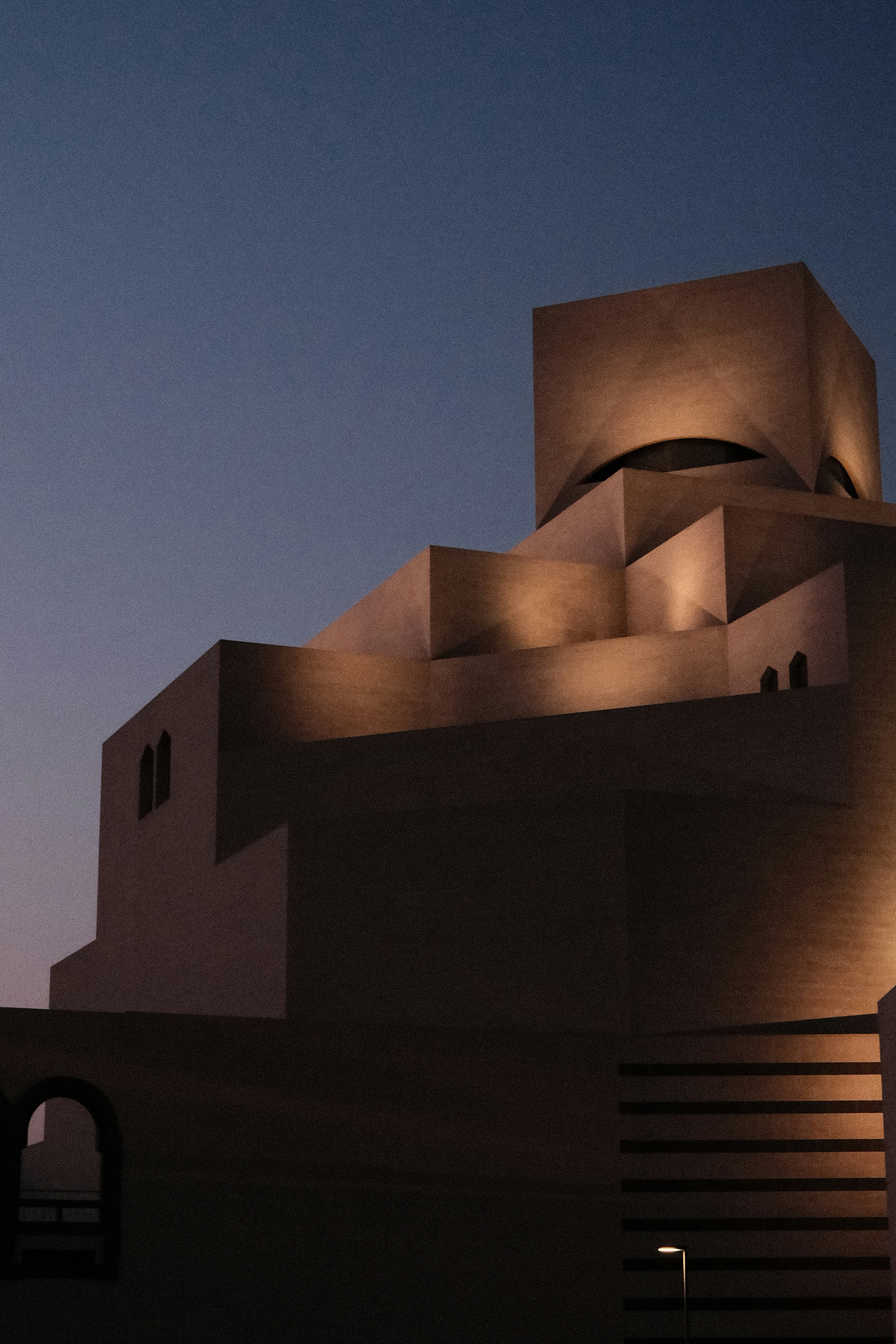 The Museum of Islamic Art in Doha illuminated against a dark blue sky