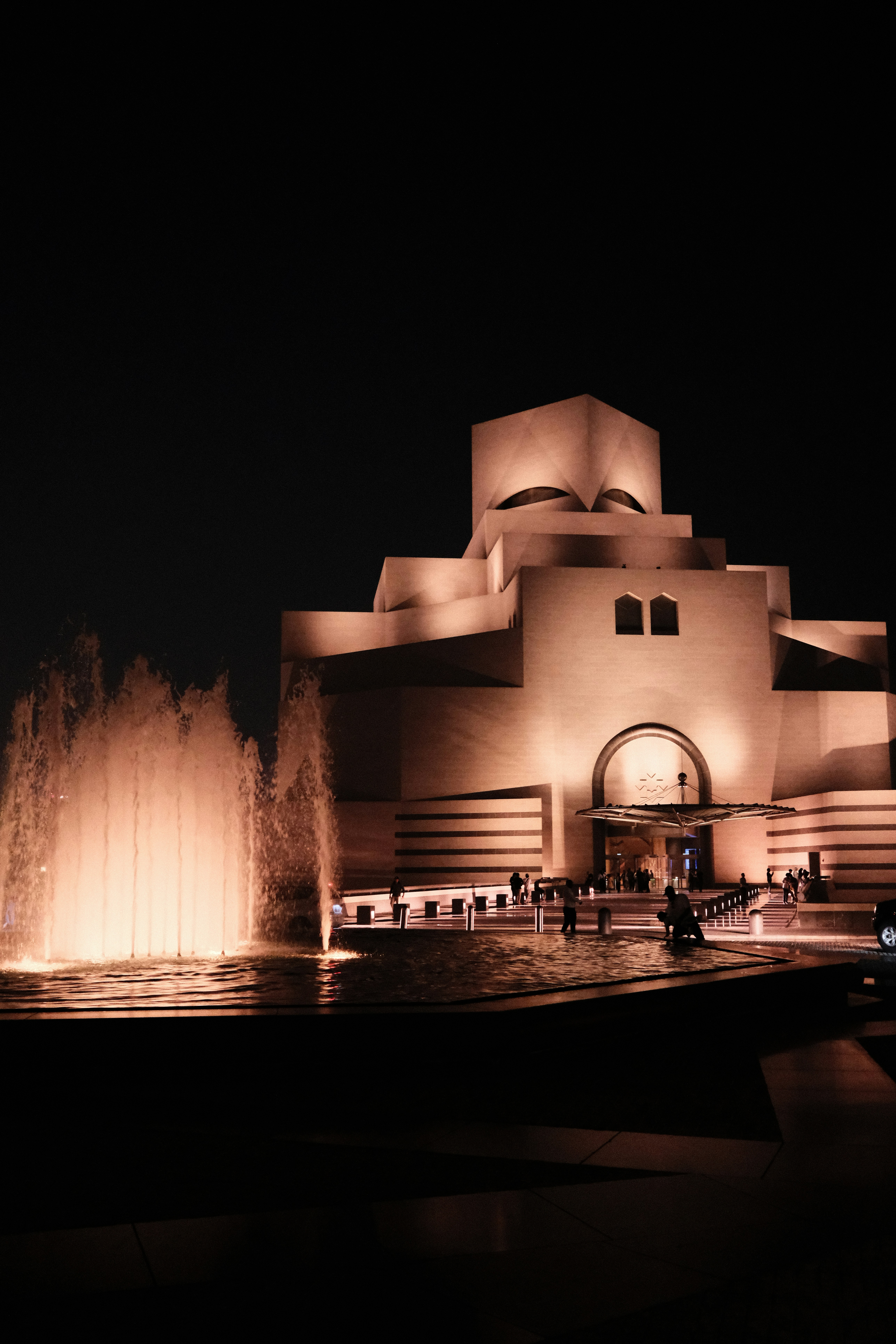 The Museum of Islamic Art in Doha illuminated at night with a fountain