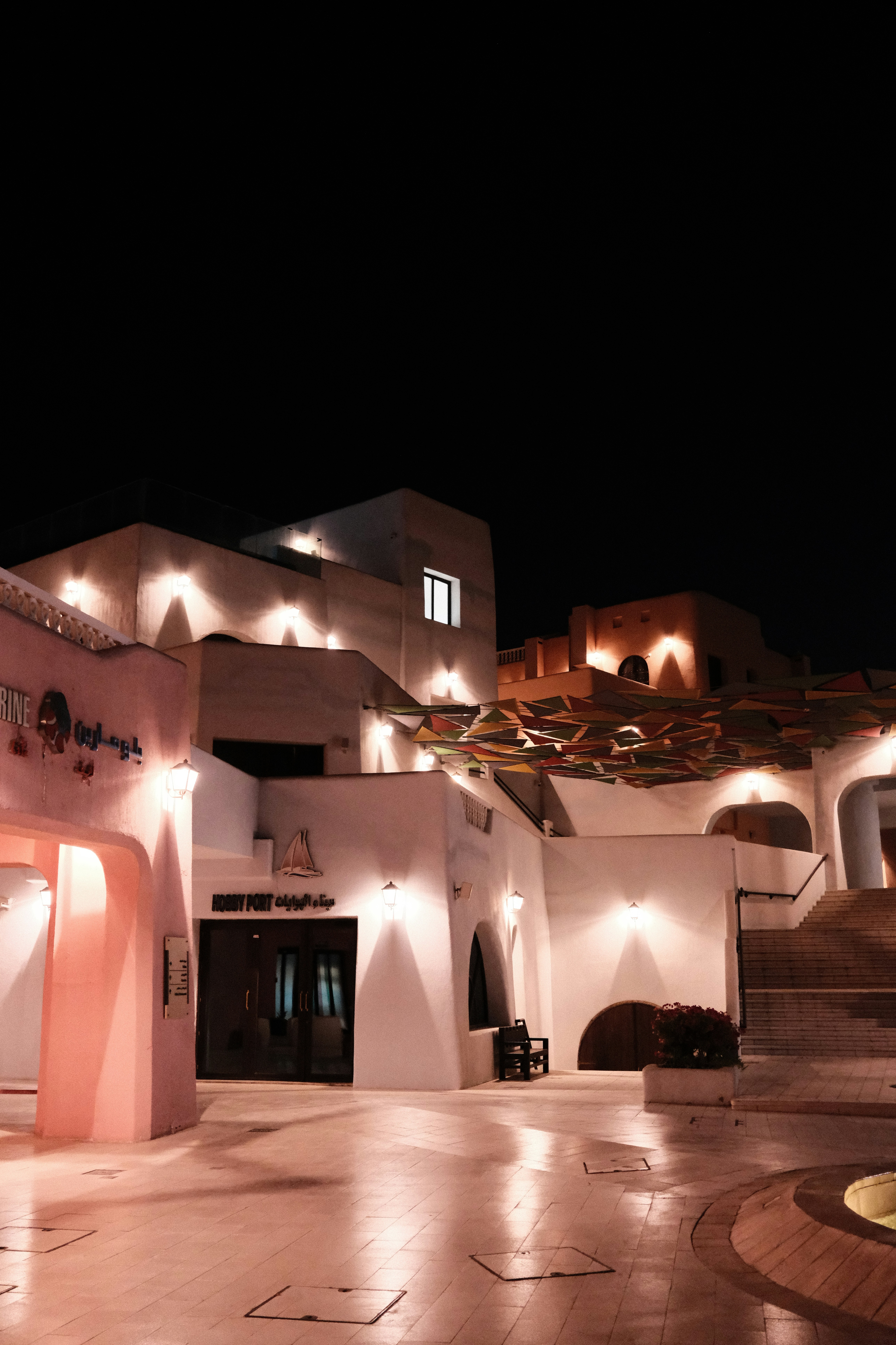 White buildings with warm exterior lighting at night near a stone staircase