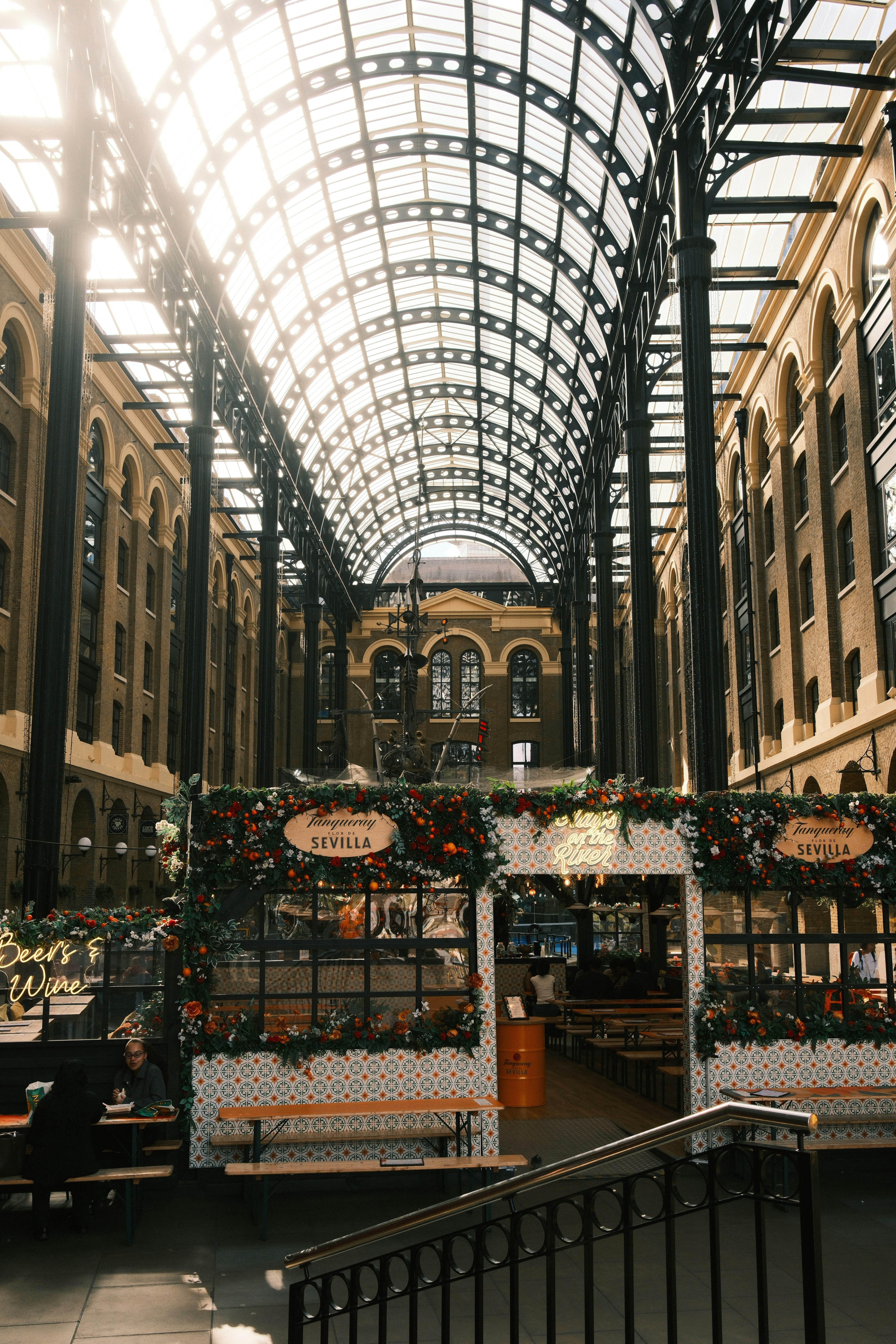 A restaurant with floral decorations under a high glass roof in a brick building