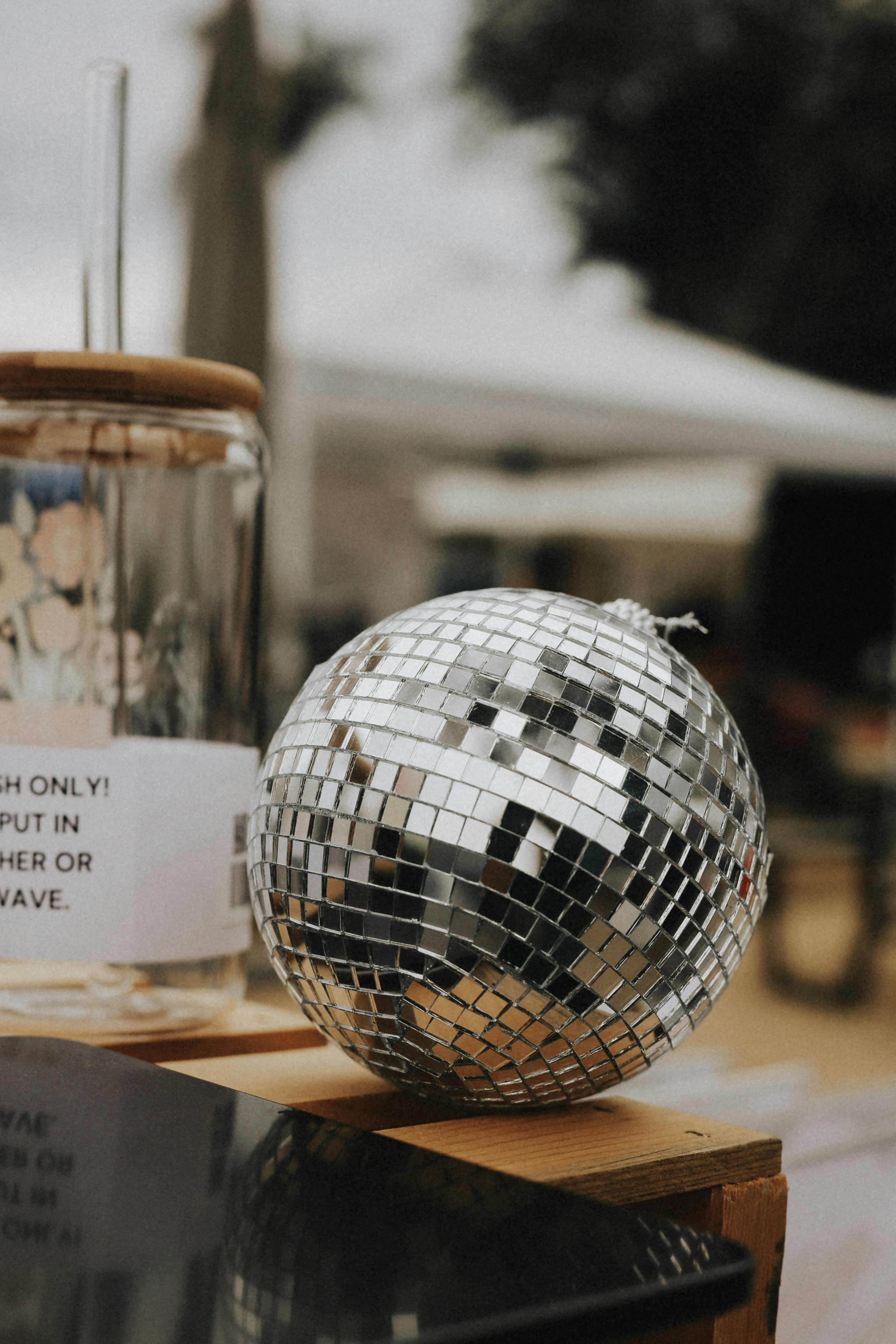 A silver disco ball on a wooden surface beside a glass tumbler