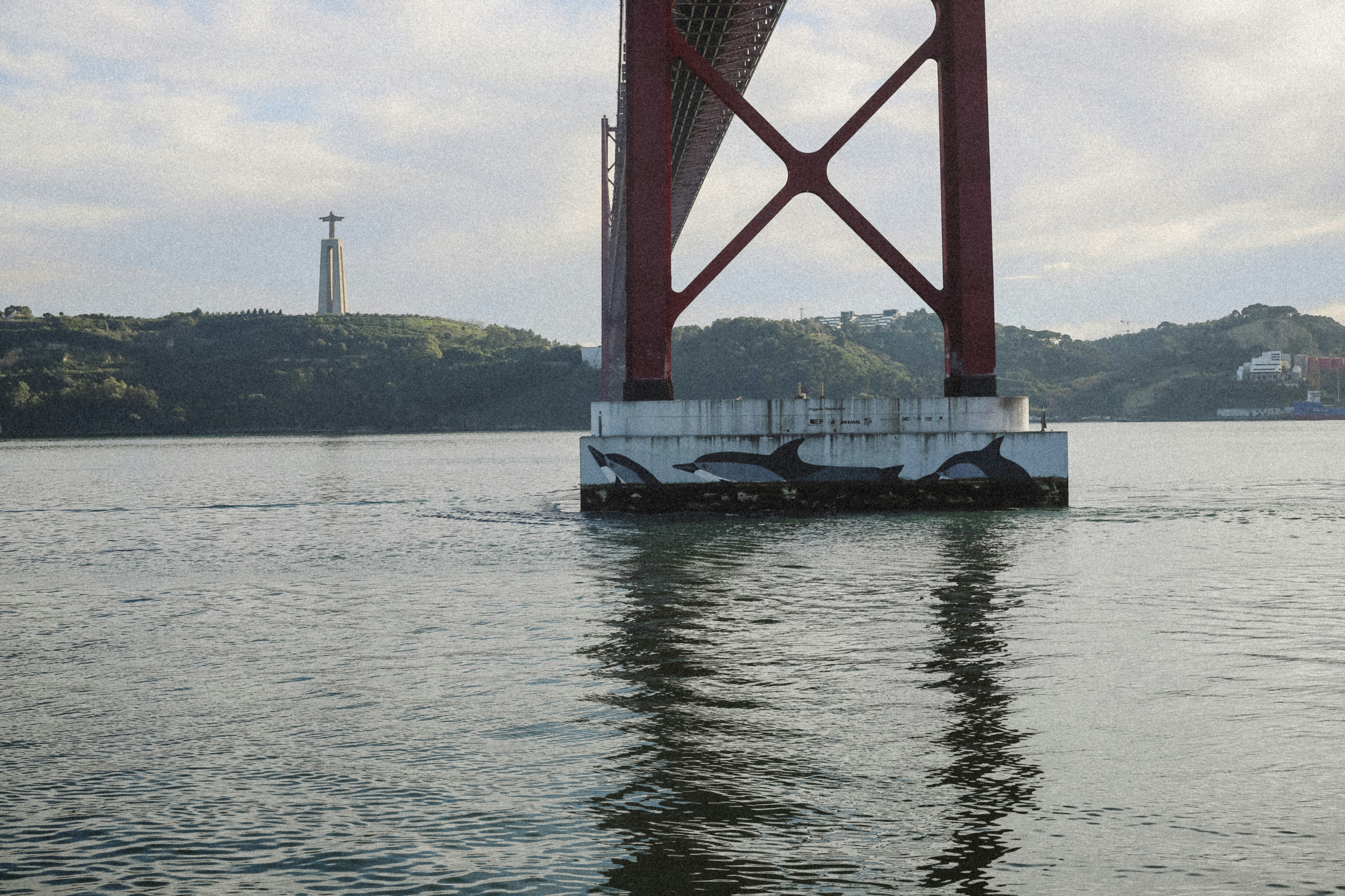 The 25 de Abril Bridge pylon with dolphin murals above the Tagus River in Lisbon