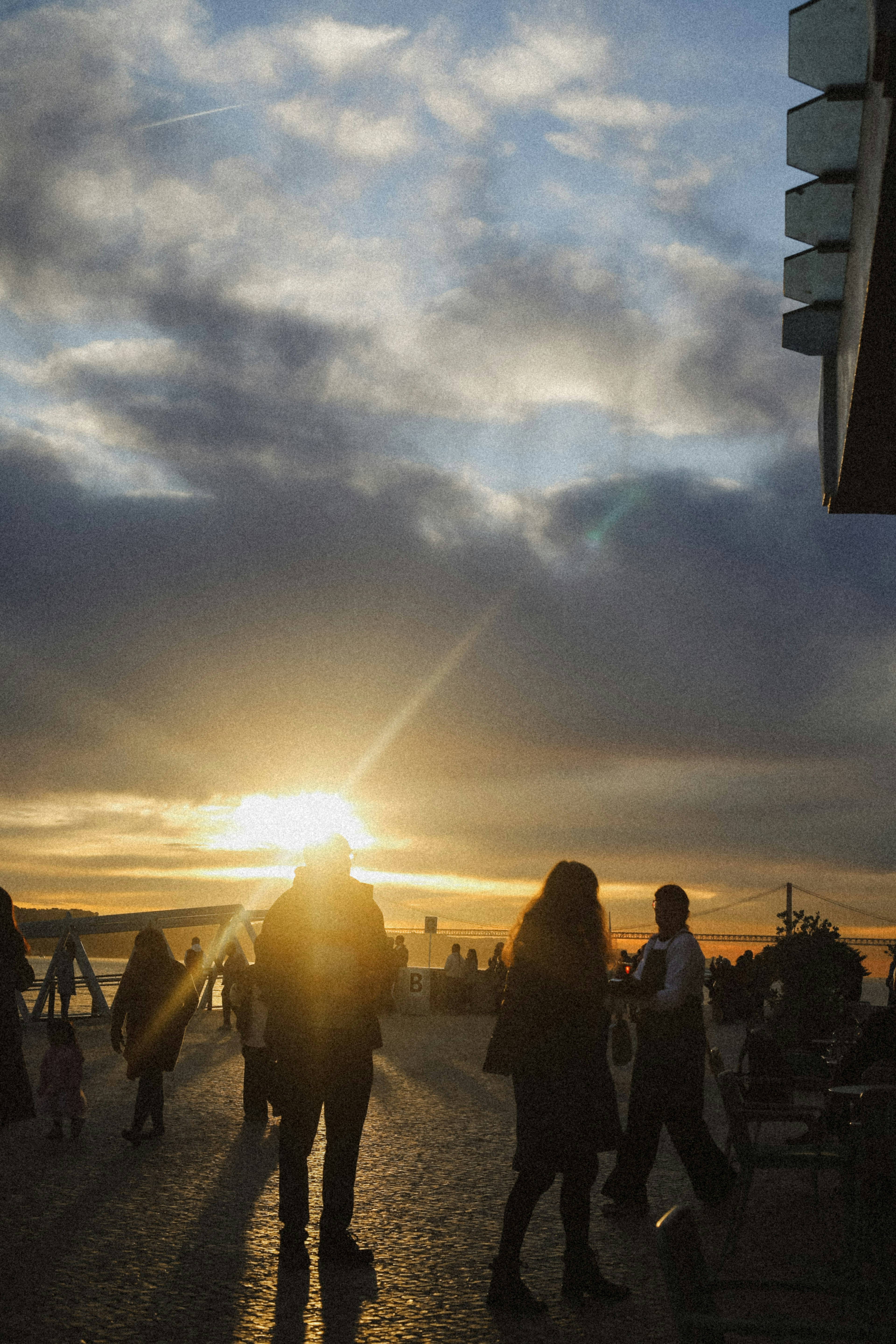 Silhouettes of people on a waterfront promenade during the golden hour