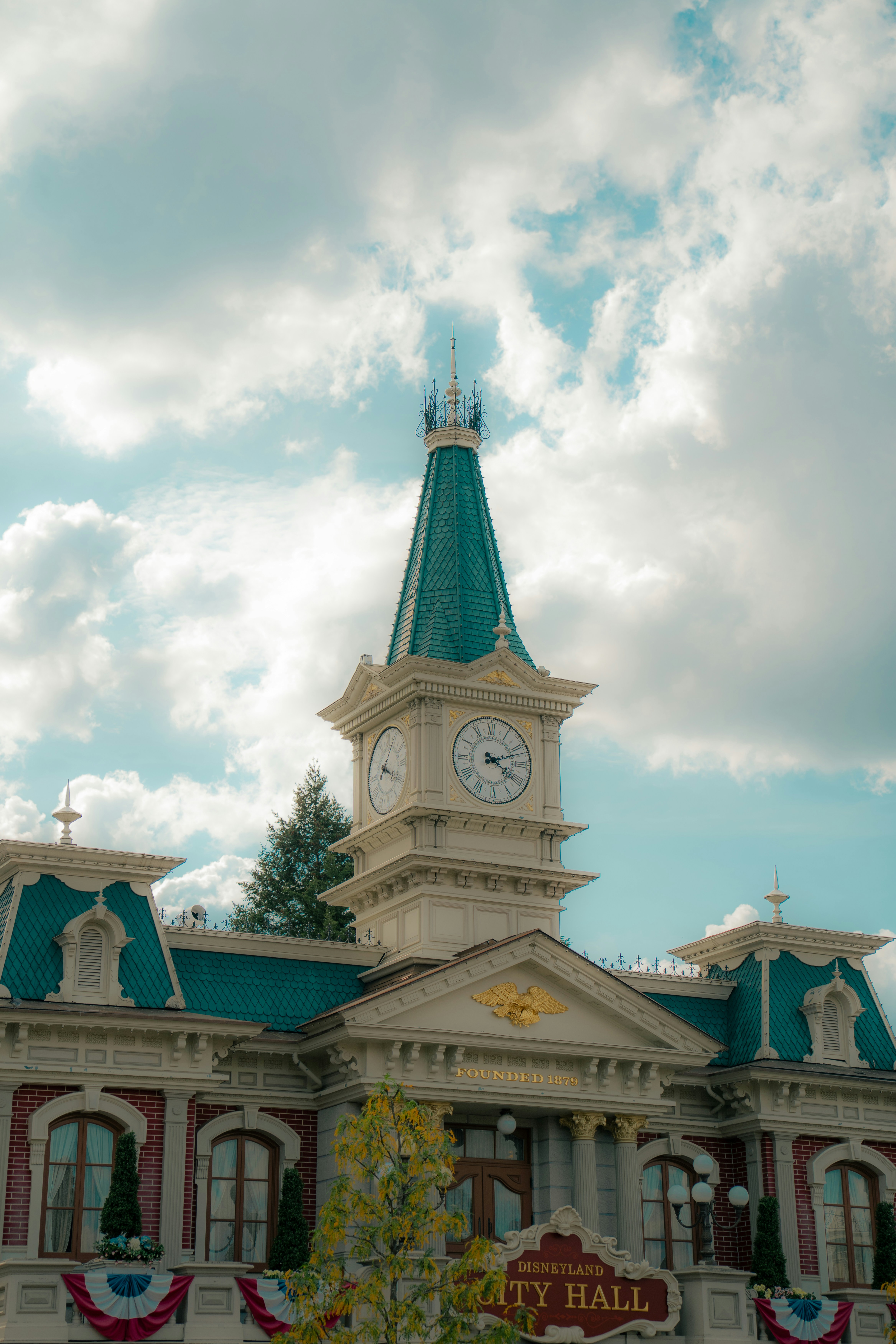 The Disneyland City Hall building with a clock tower under a cloudy blue sky