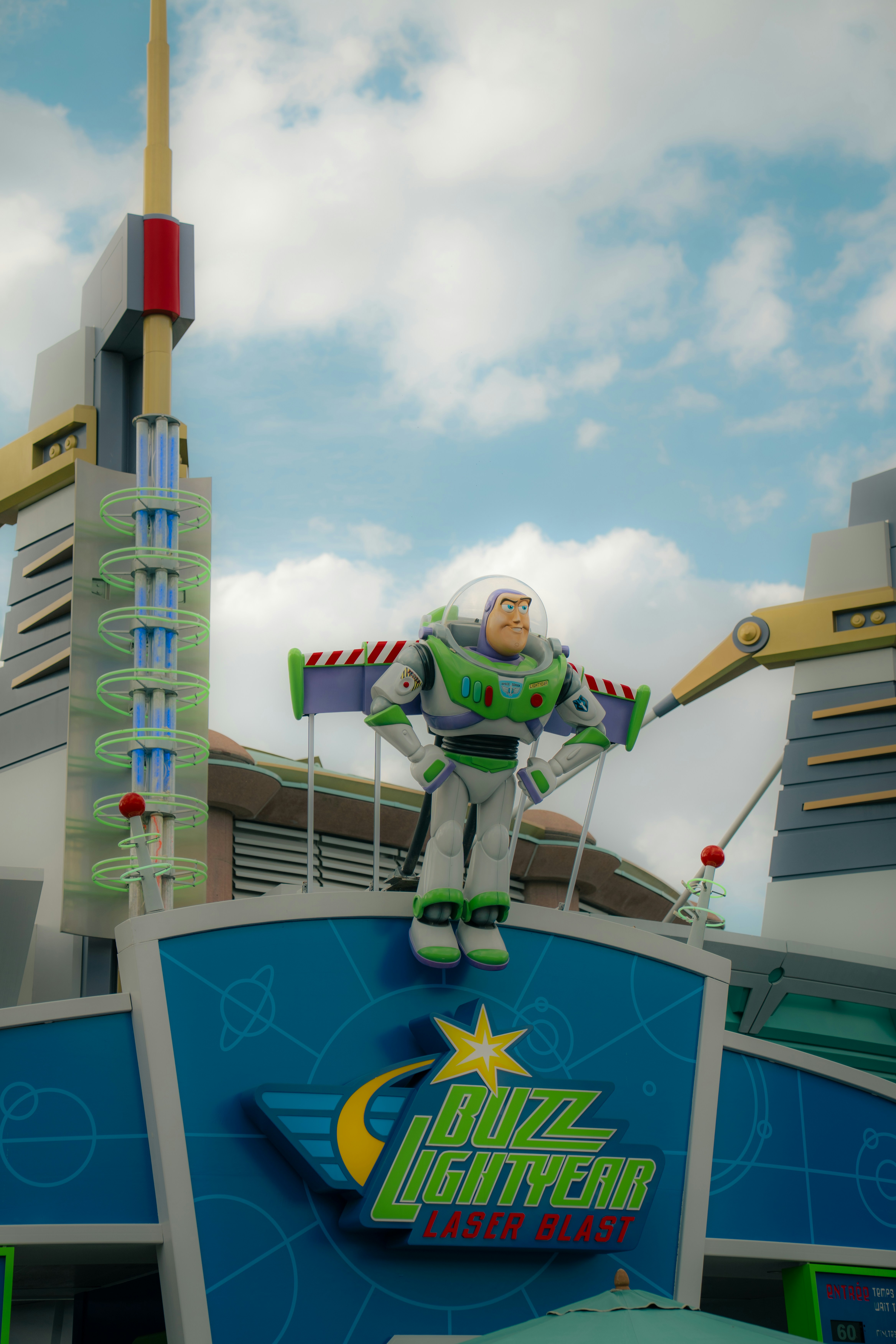A Buzz Lightyear figure atop a blue sign for Buzz Lightyear Laser Blast