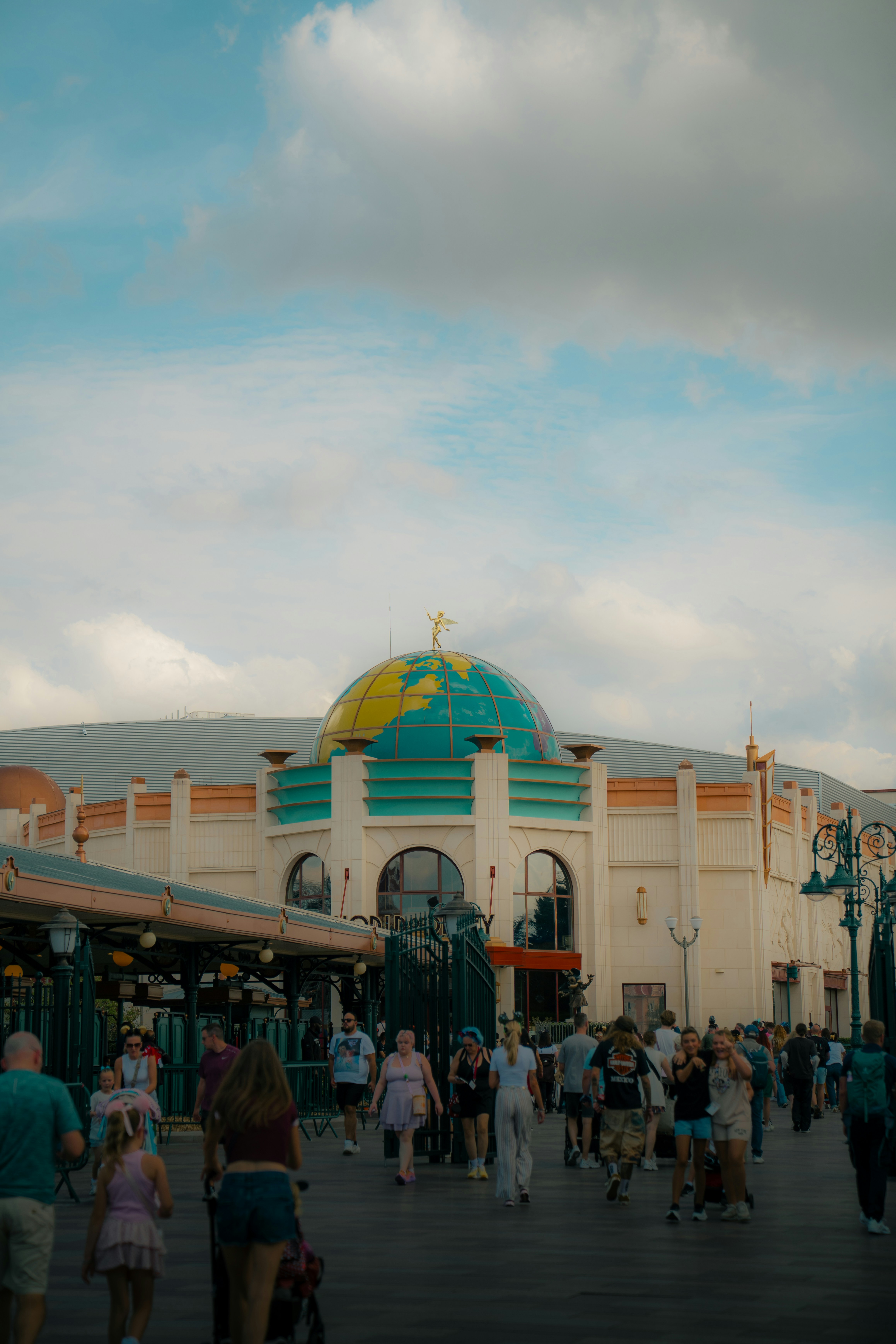 A crowd of people walking toward a building with a large globe dome