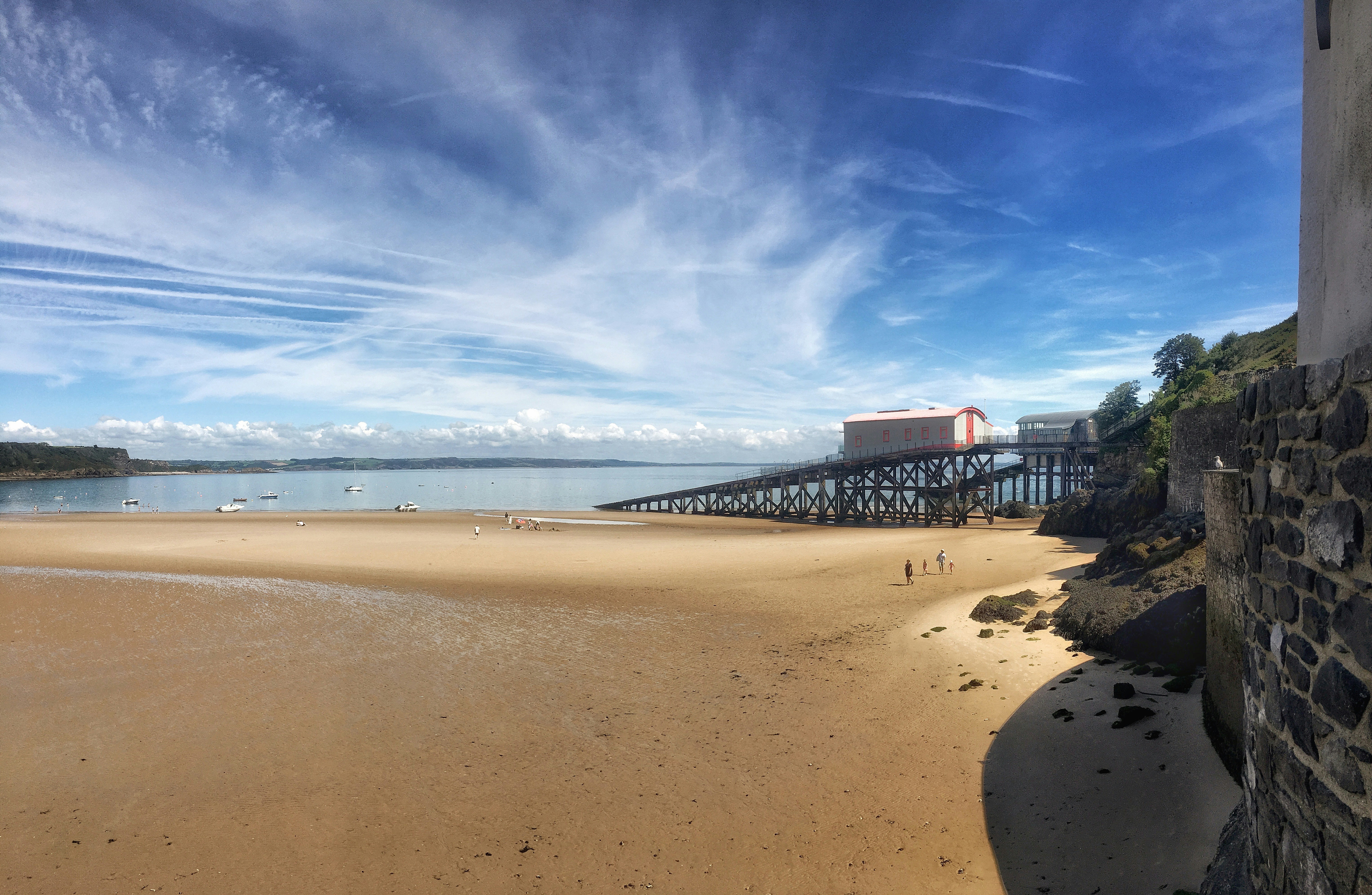 A lifeboat station on stilts above a sandy beach under a blue sky