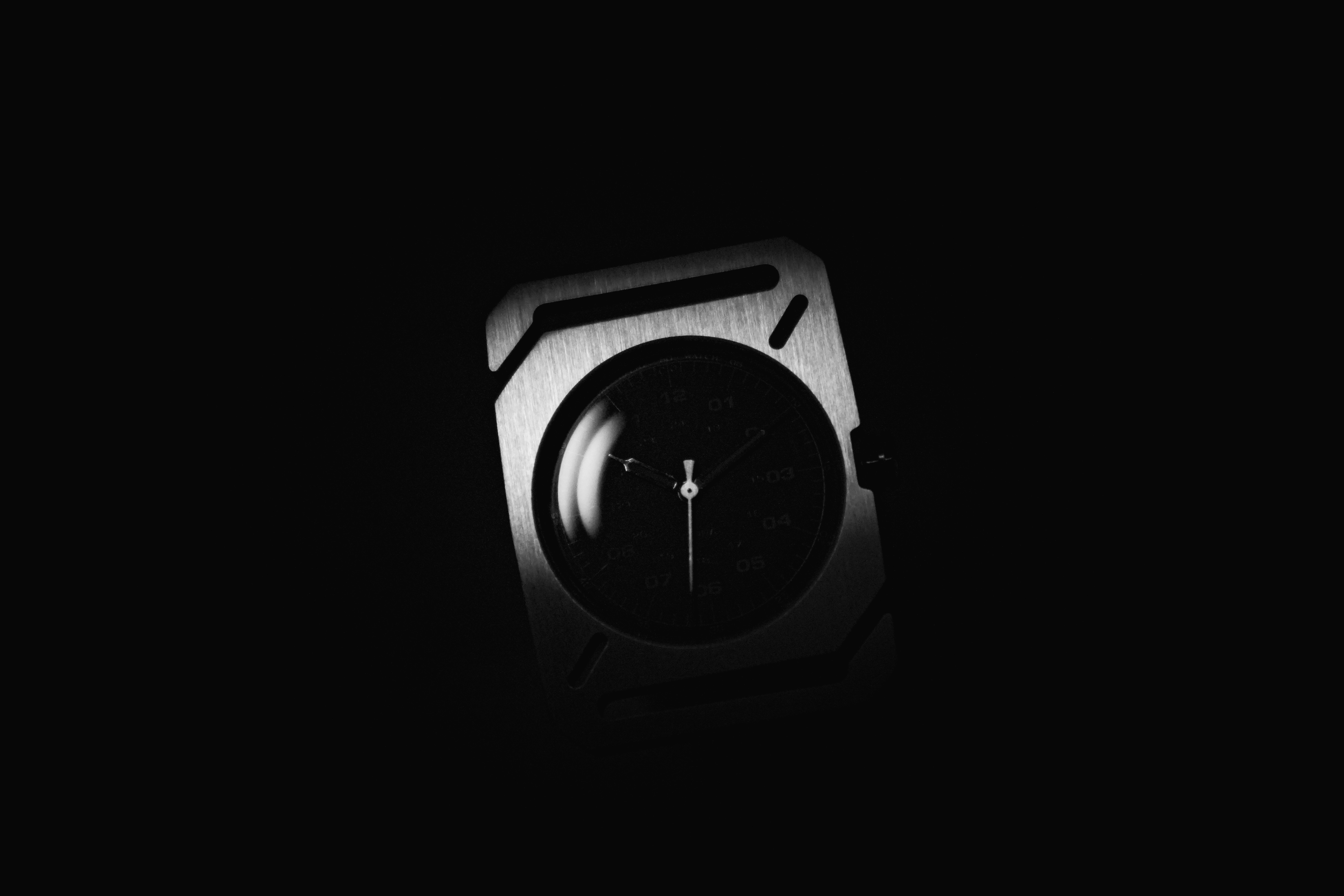 A brushed metal wristwatch with a circular face against a dark background