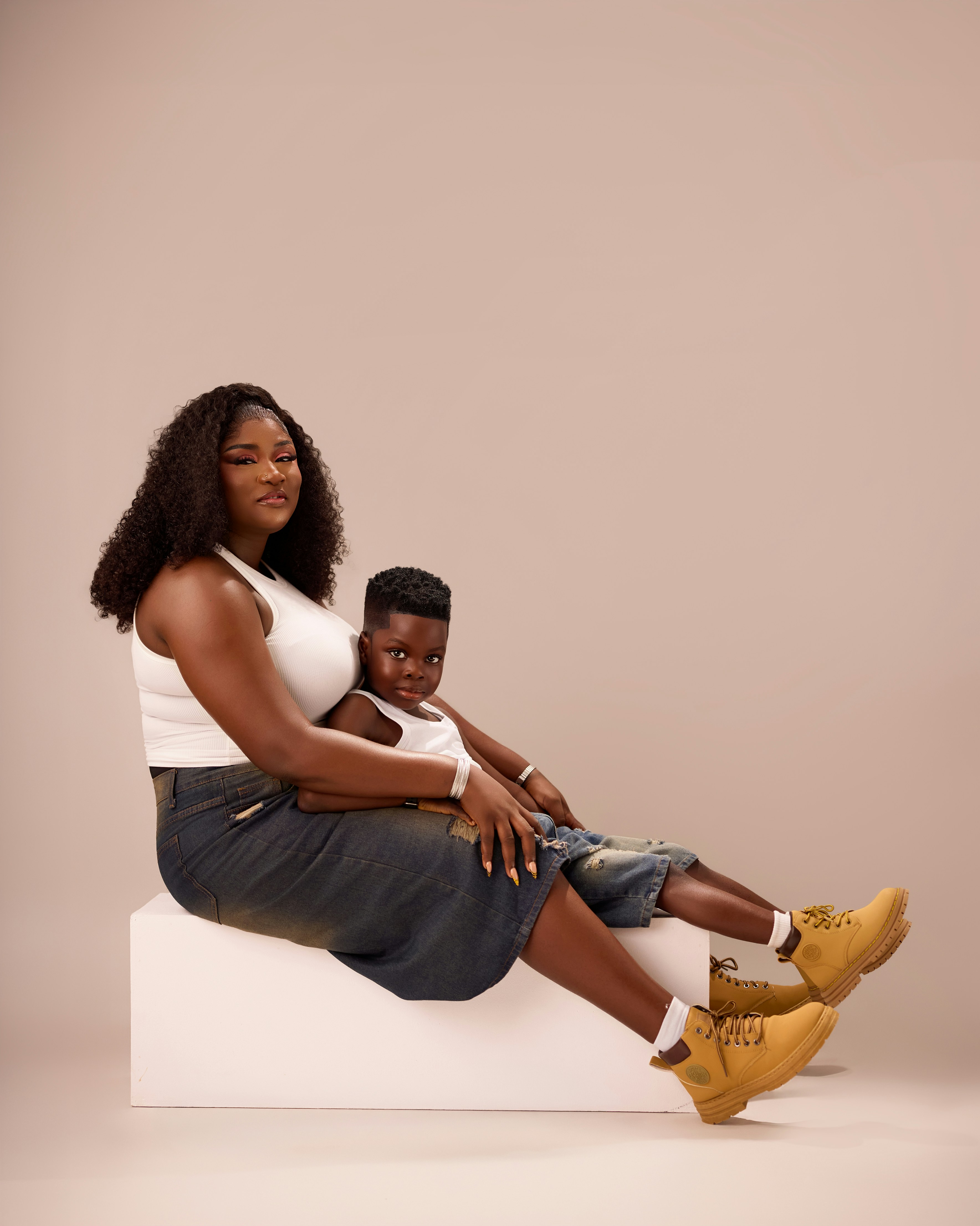 A woman and a child in white tank tops and denim shorts sitting together