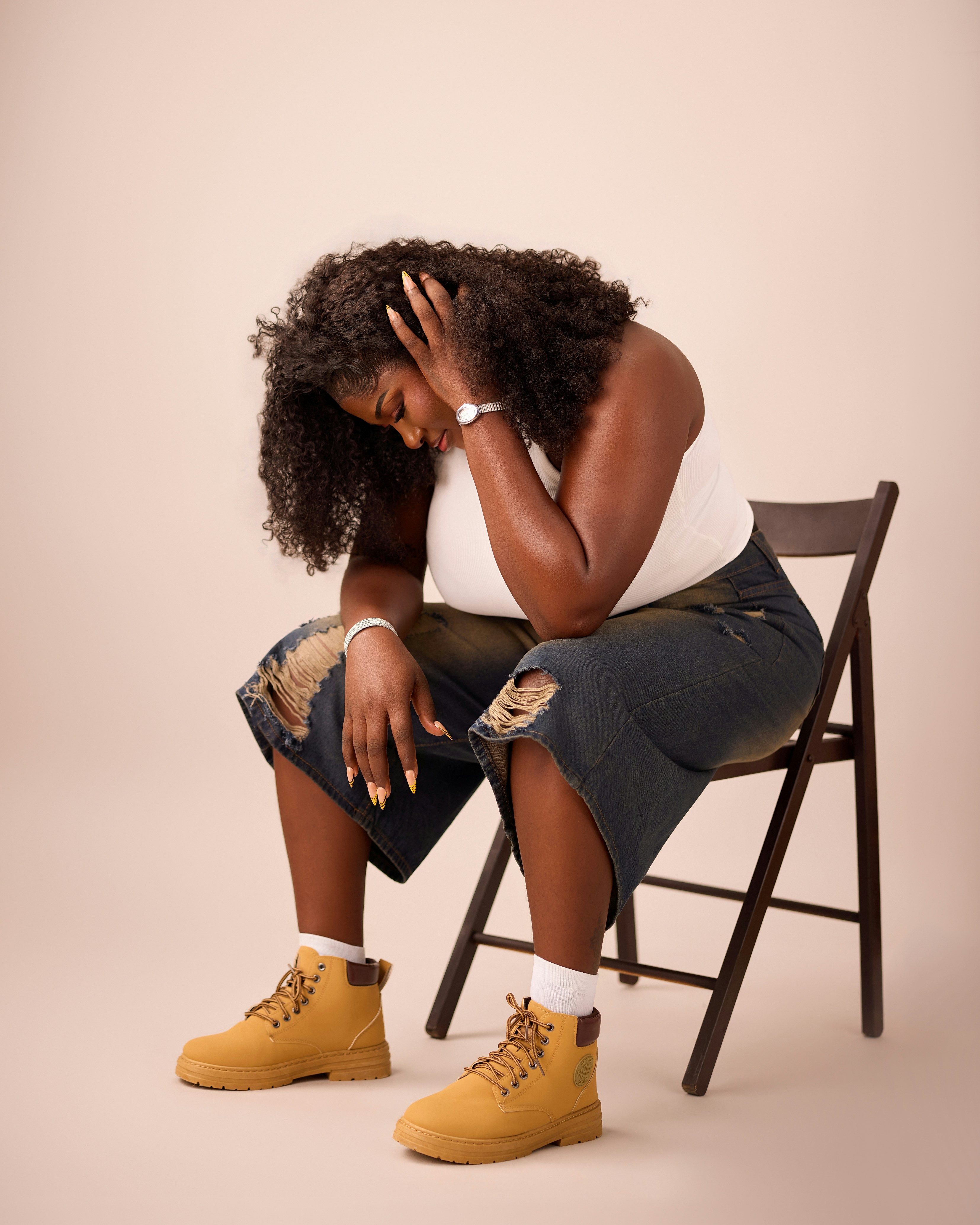A woman with curly hair in a white tank top and distressed jeans