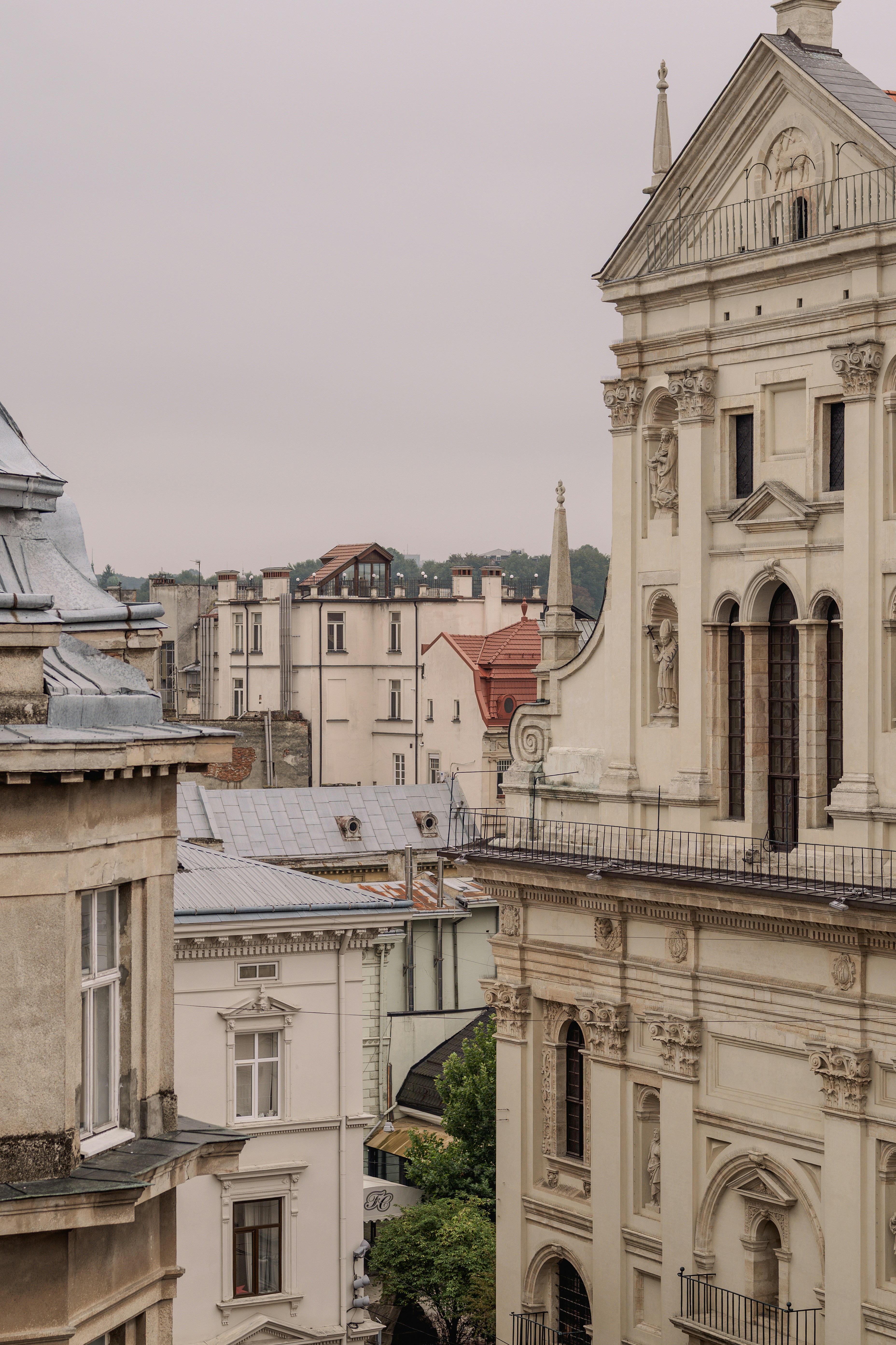 Ornate cream-colored church facade overlooking a dense urban cityscape with historic buildings