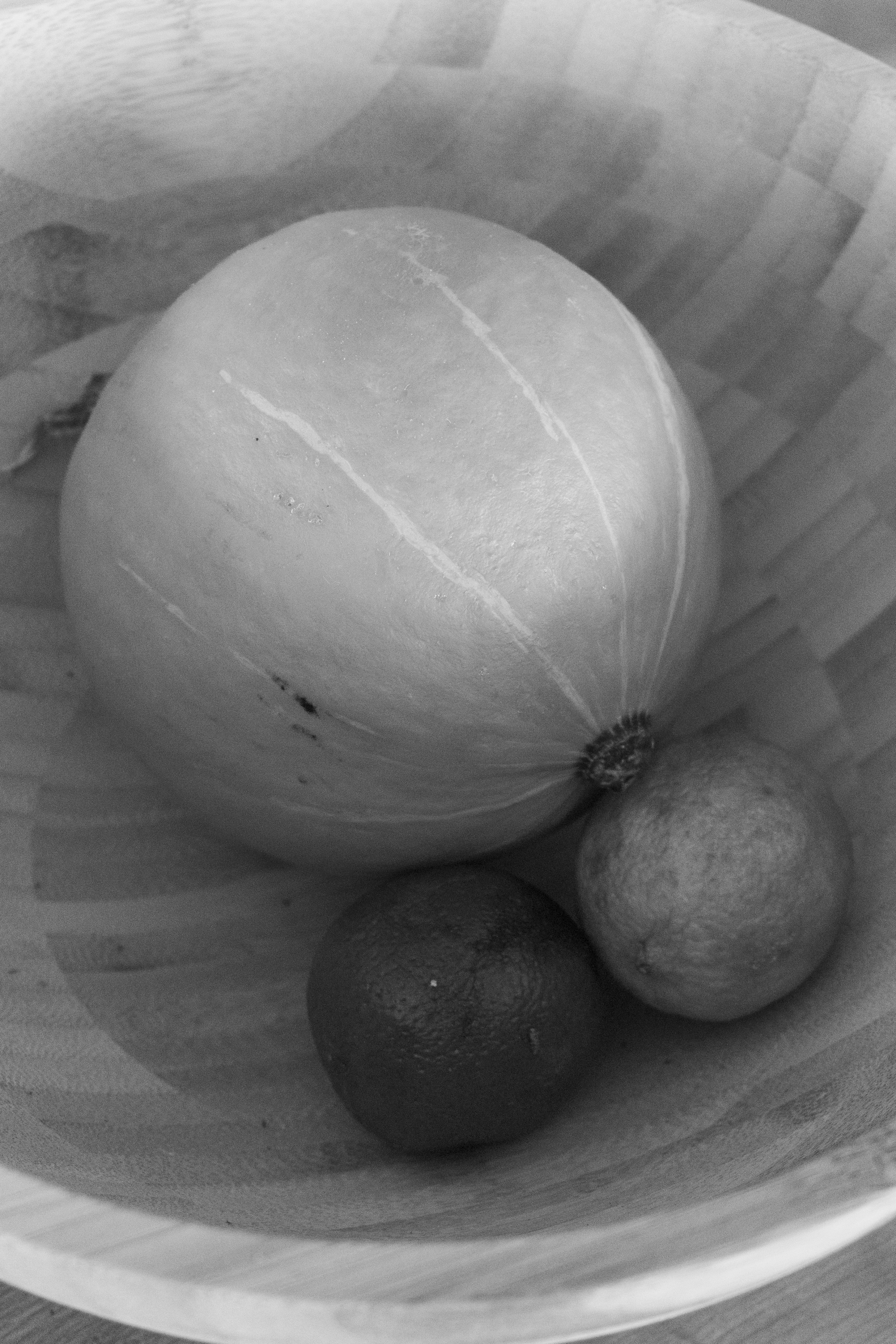 Ein Kürbis und zwei Zitrusfrüchte in einer Holzschale