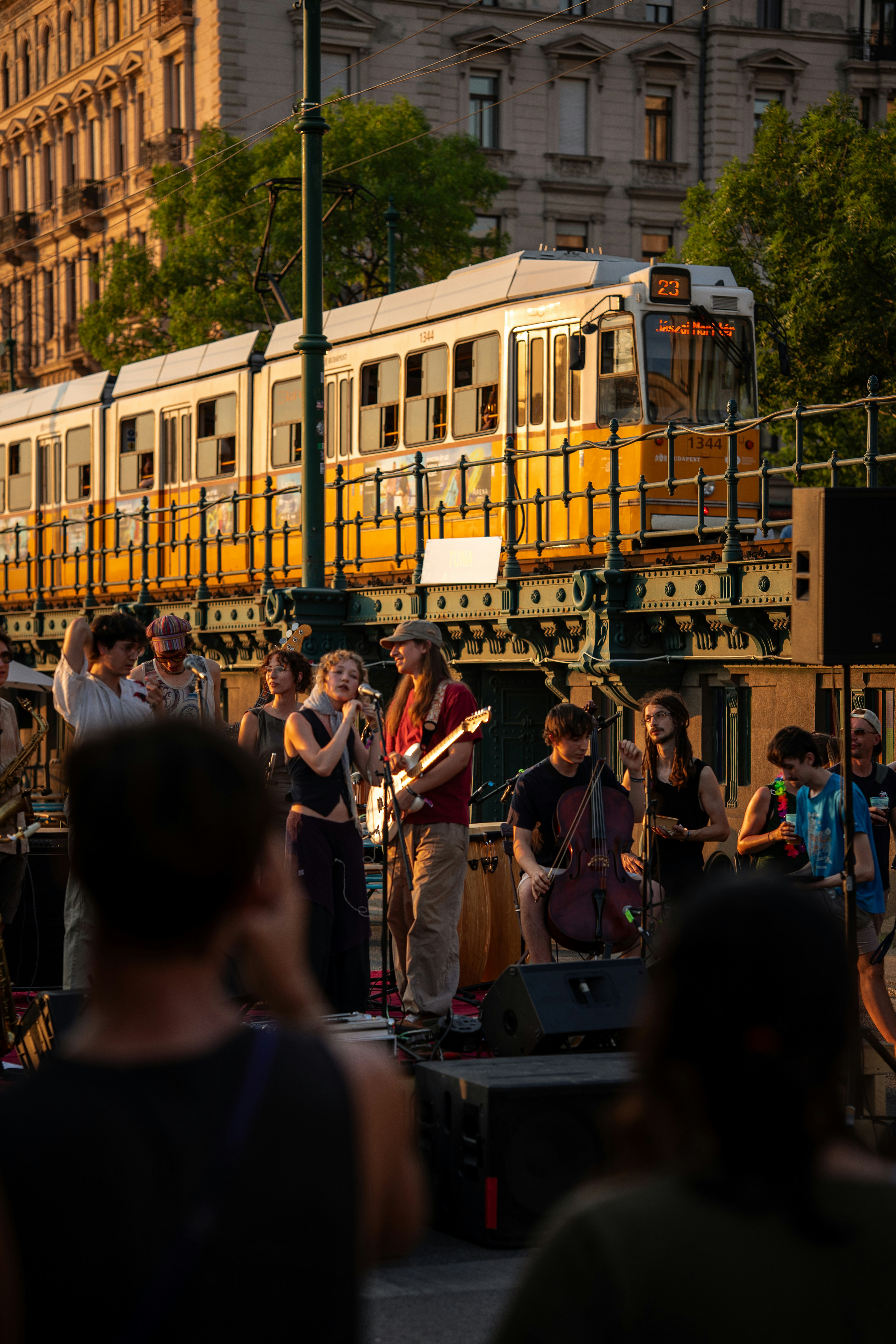 A band performing on a street in Budapest with a yellow tram passing behind