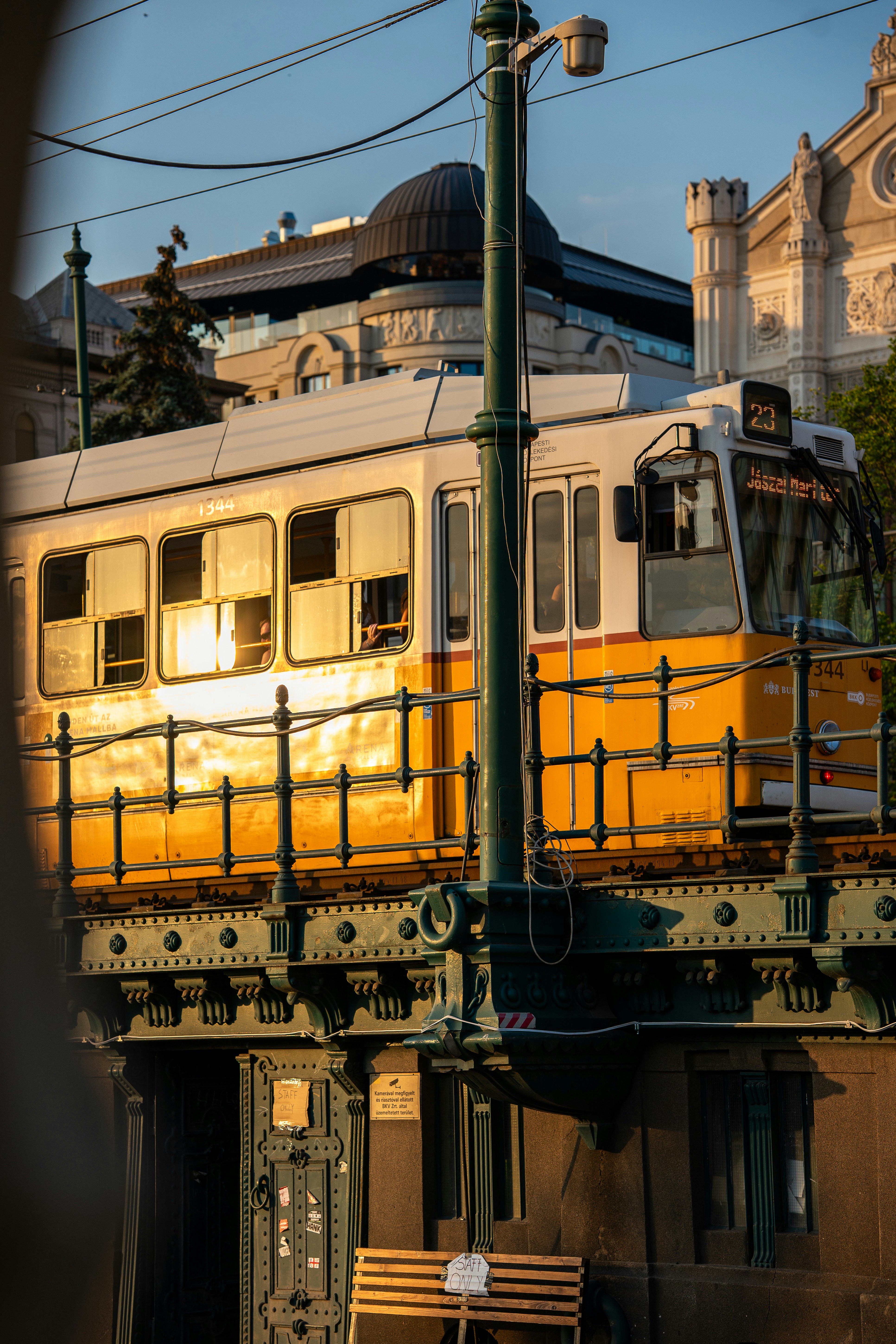A yellow tram crossing a bridge in Budapest during the golden hour