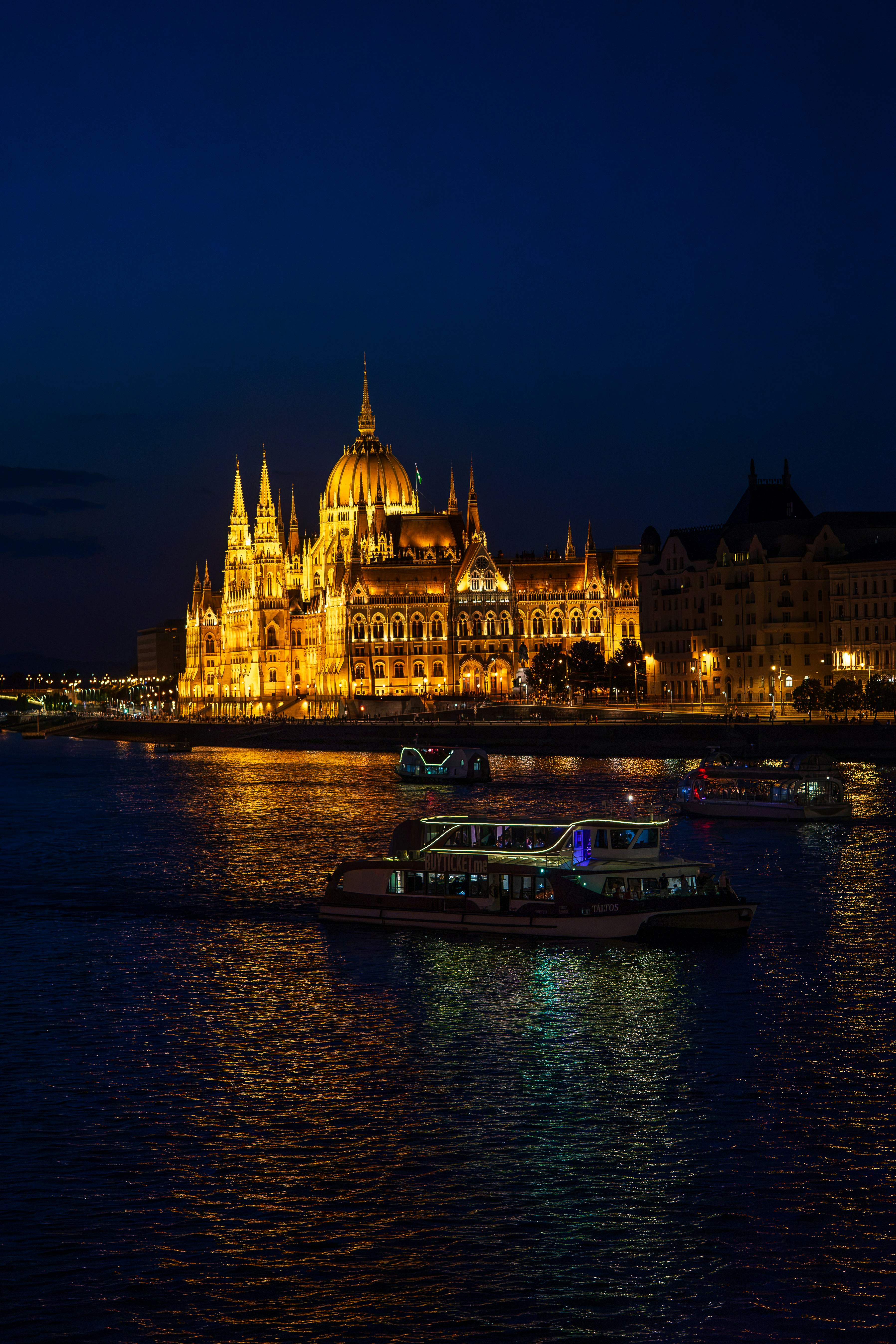 The Hungarian Parliament Building illuminated at night beside the Danube river in Budapest