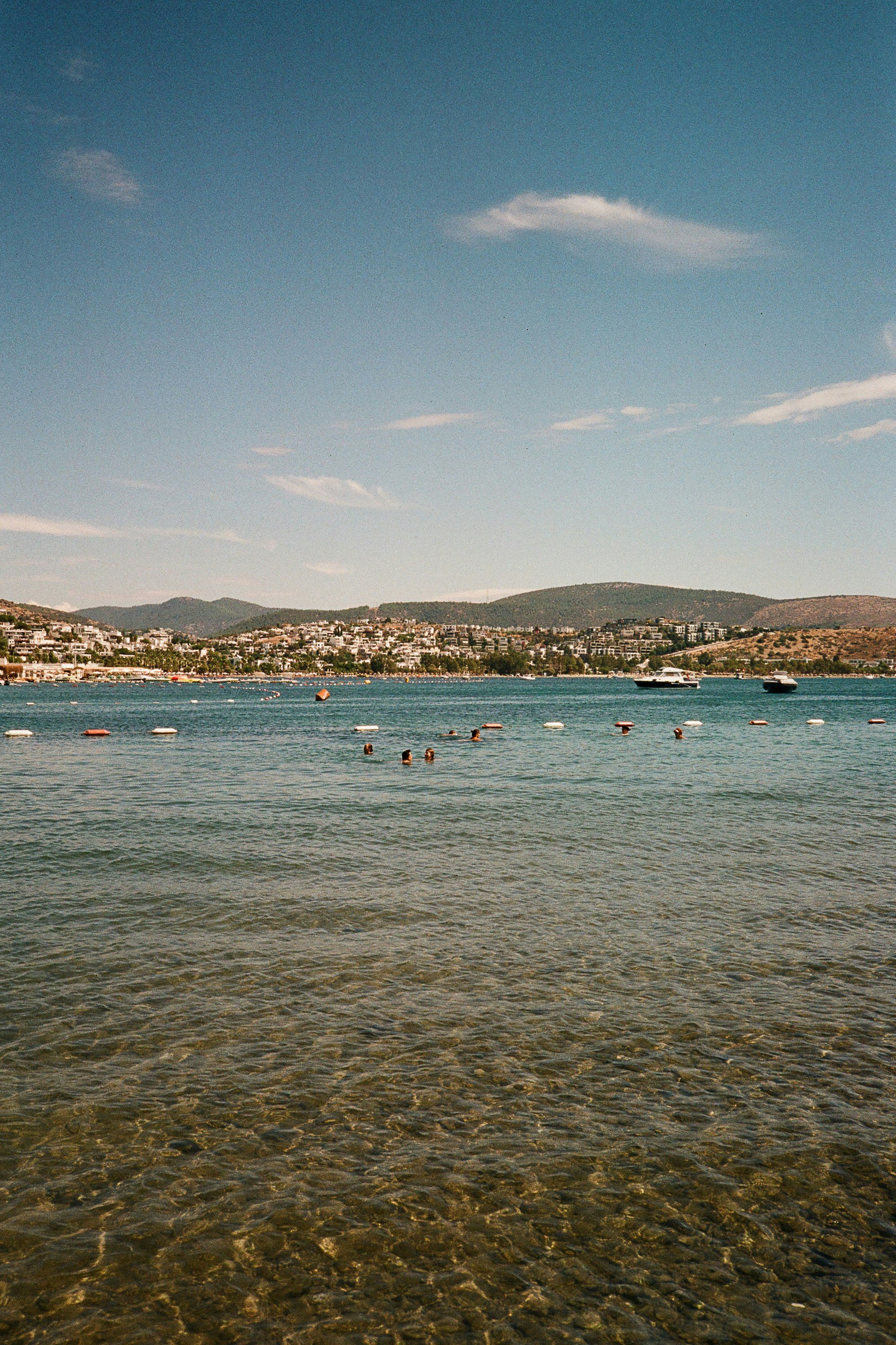 People swimming in the clear blue water of a bay in Bodrum, Türkiye