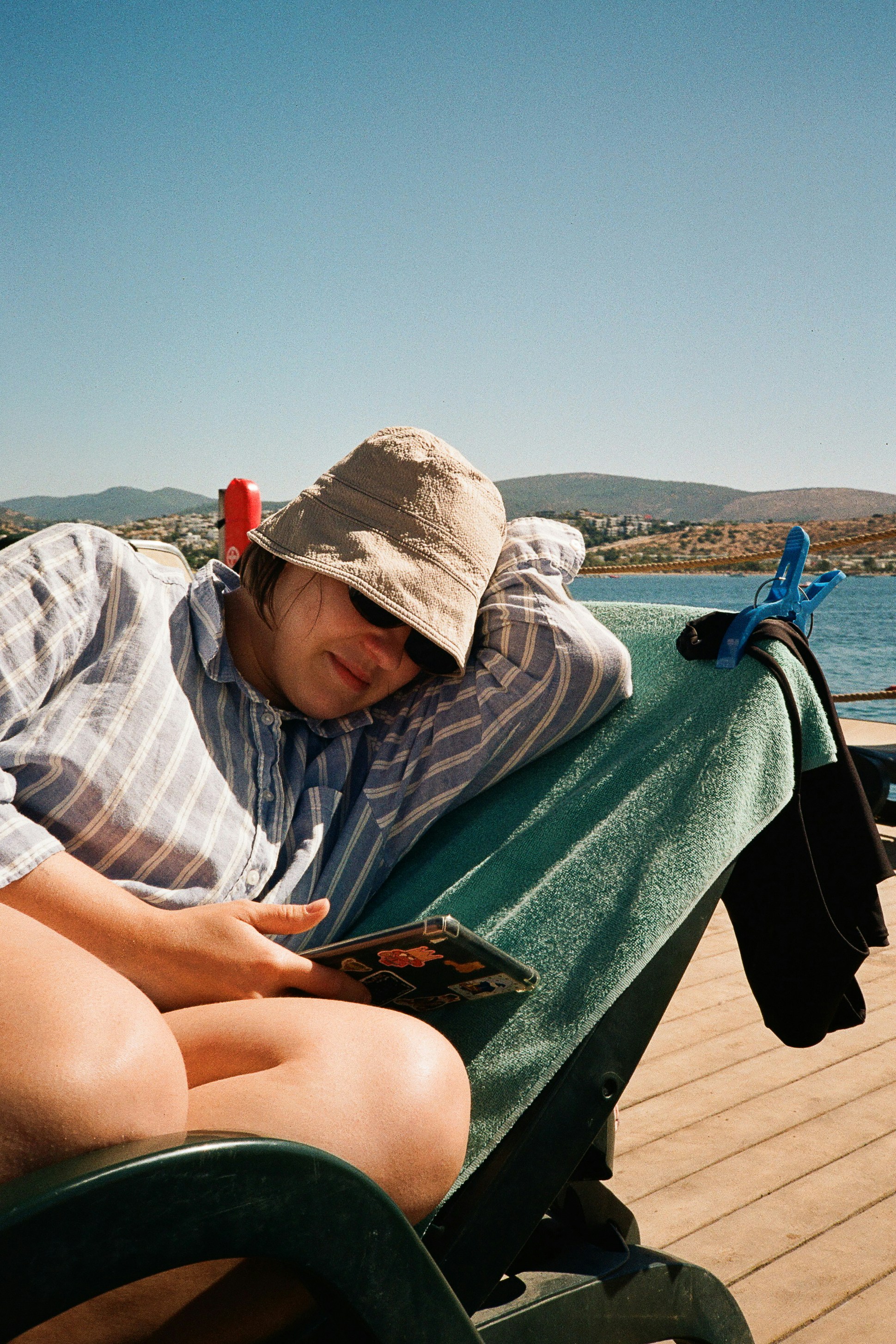 A person in a bucket hat and striped shirt relaxing on a deck in Bodrum