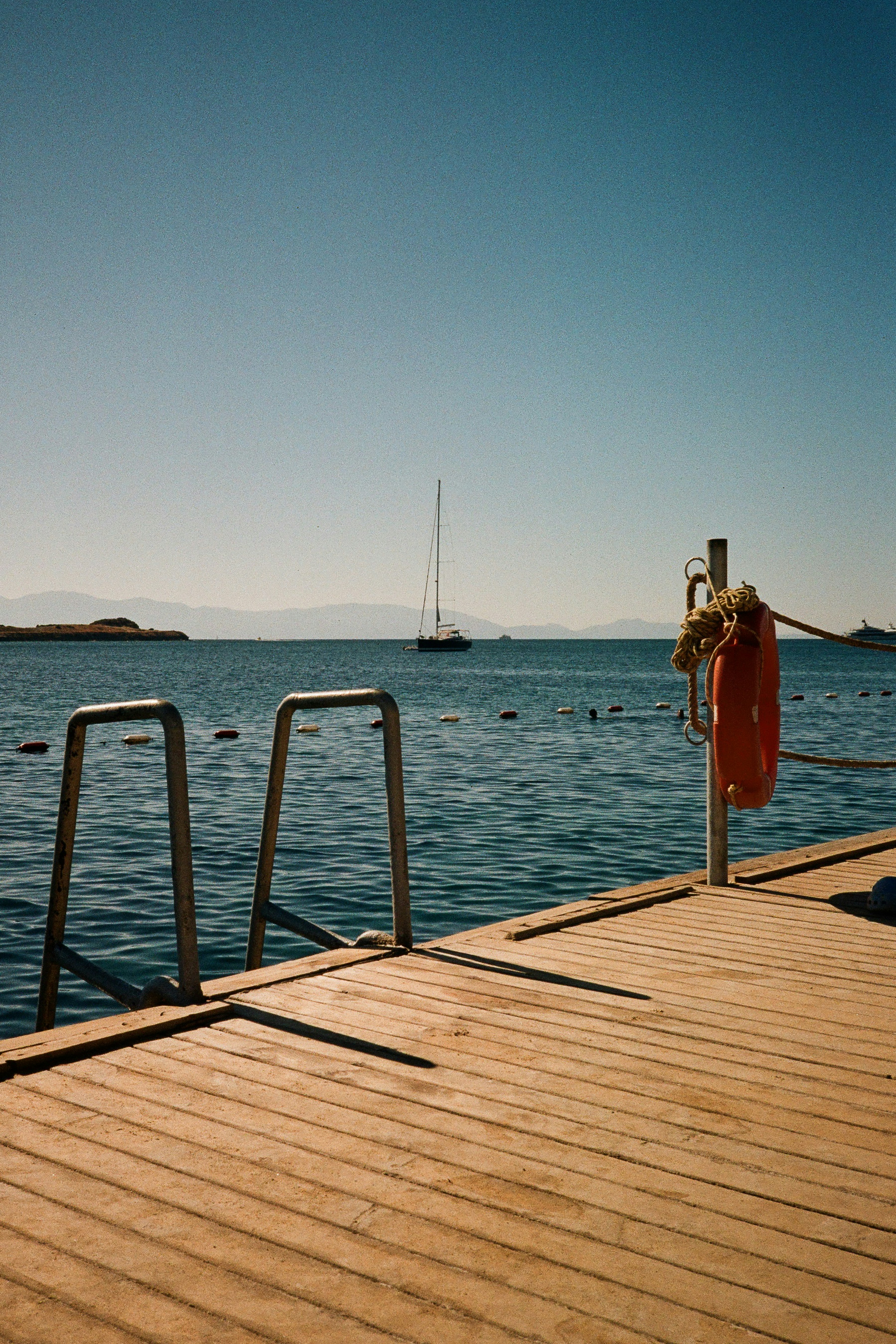 A wooden pier with a lifebuoy and metal ladder in Bodrum, Türkiye