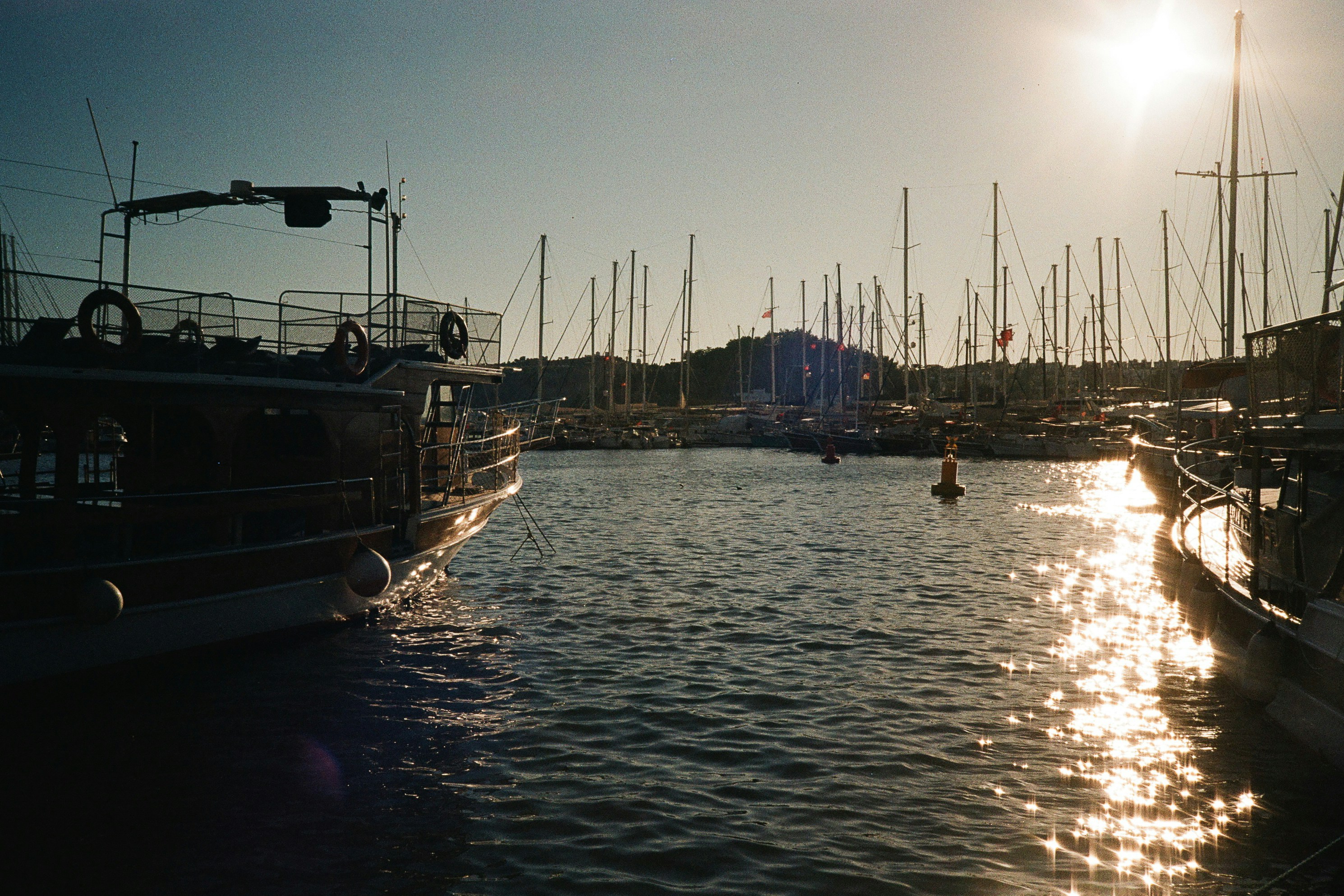 Boats moored in a marina in Bodrum under a bright low sun