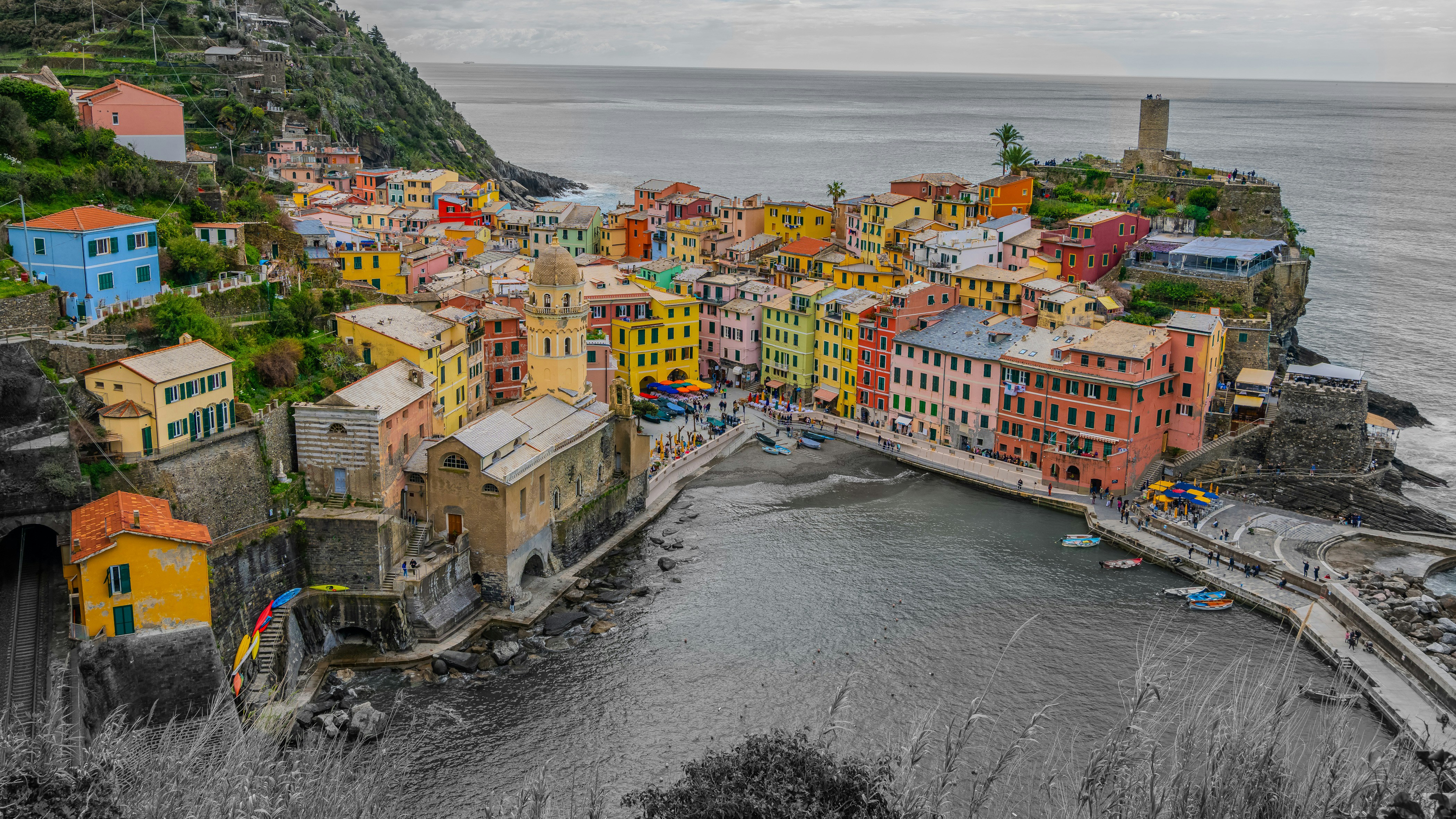 Colorful houses clustered on a cliffside above the harbor in Vernazza, a coastal stop some northern Italy tours add beyond Rome-Florence-Venice