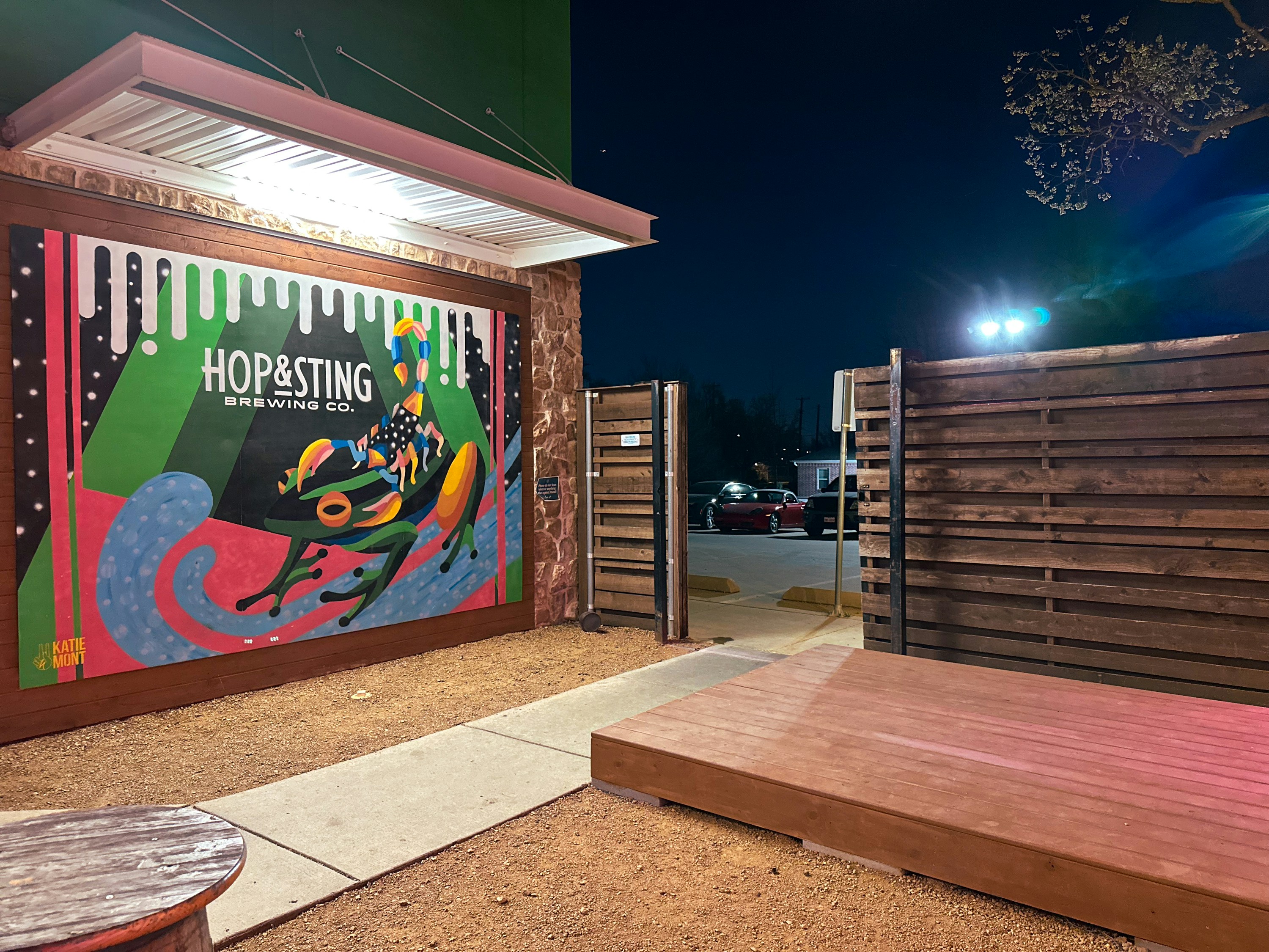 A colorful mural of a frog and scorpion on a brewery wall at night