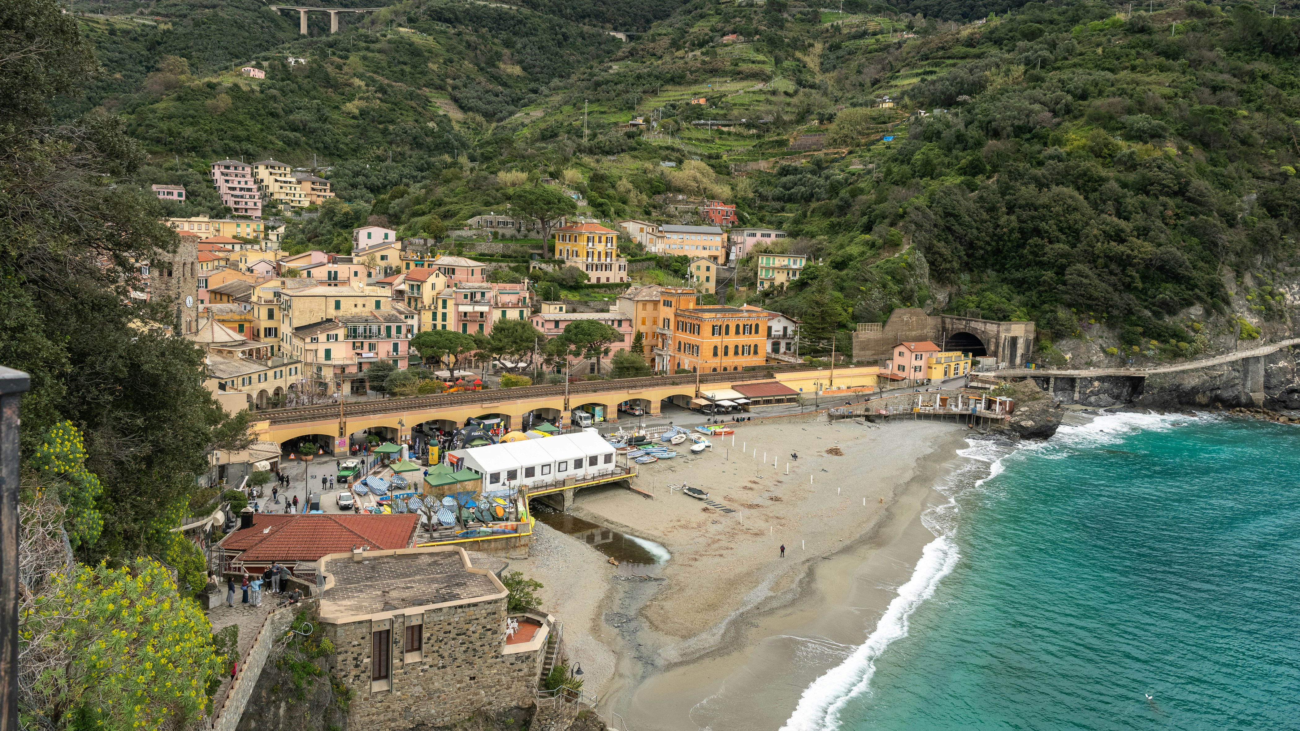 A coastal village with colorful buildings nestled on a hillside above a sandy beach