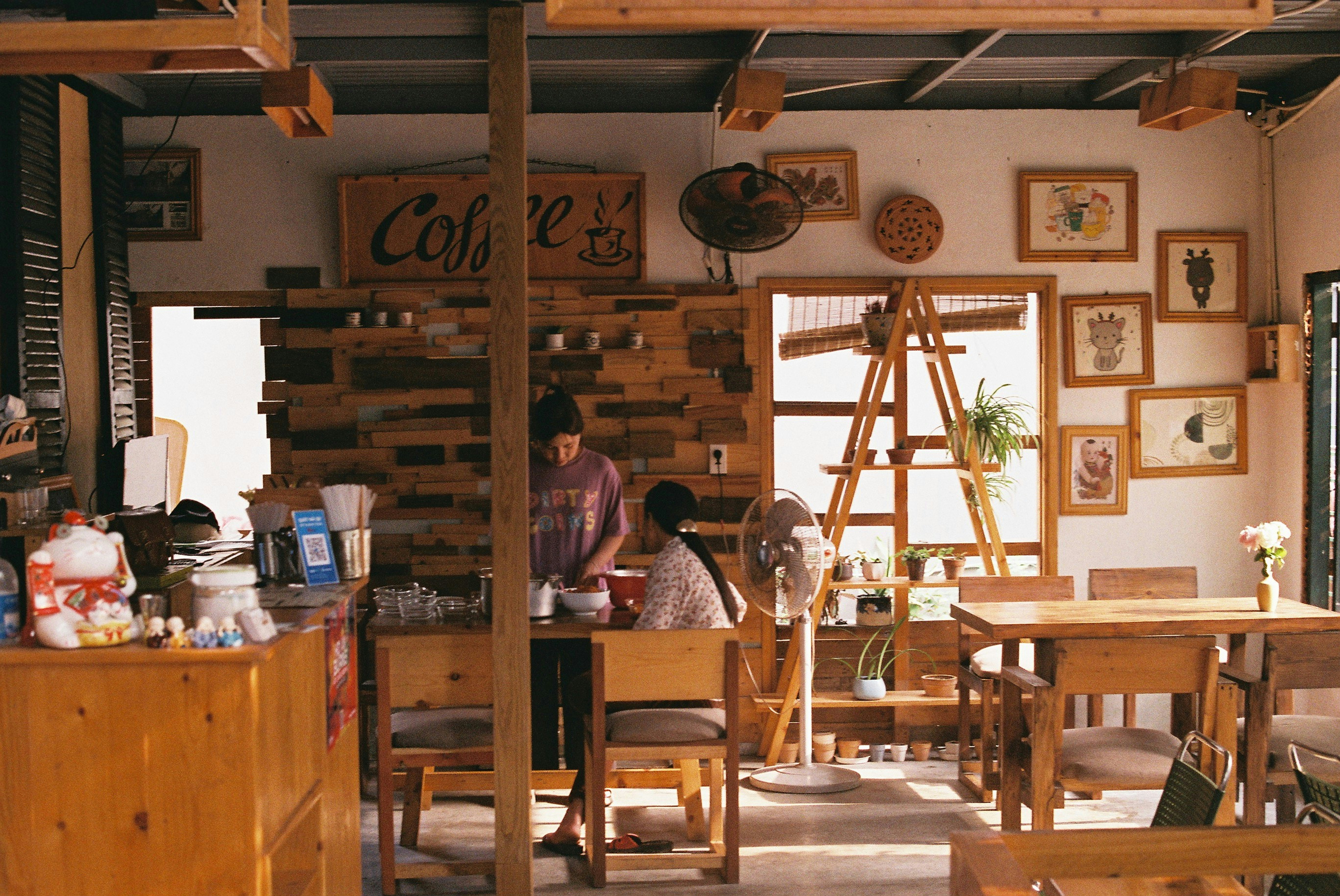 Two people preparing food in a rustic wooden cafe with framed wall art