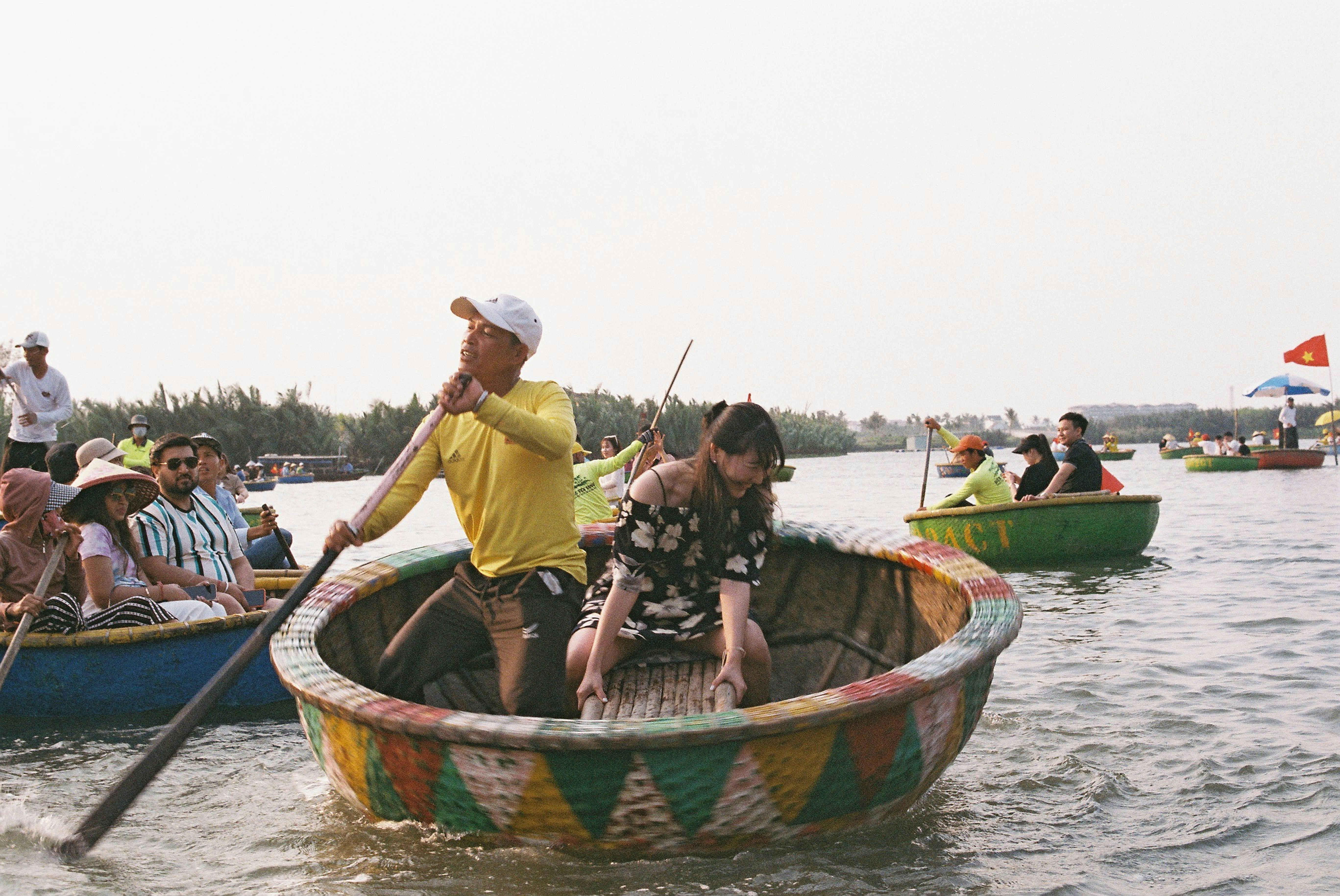 A man in a yellow shirt rowing a round basket boat in Vietnam