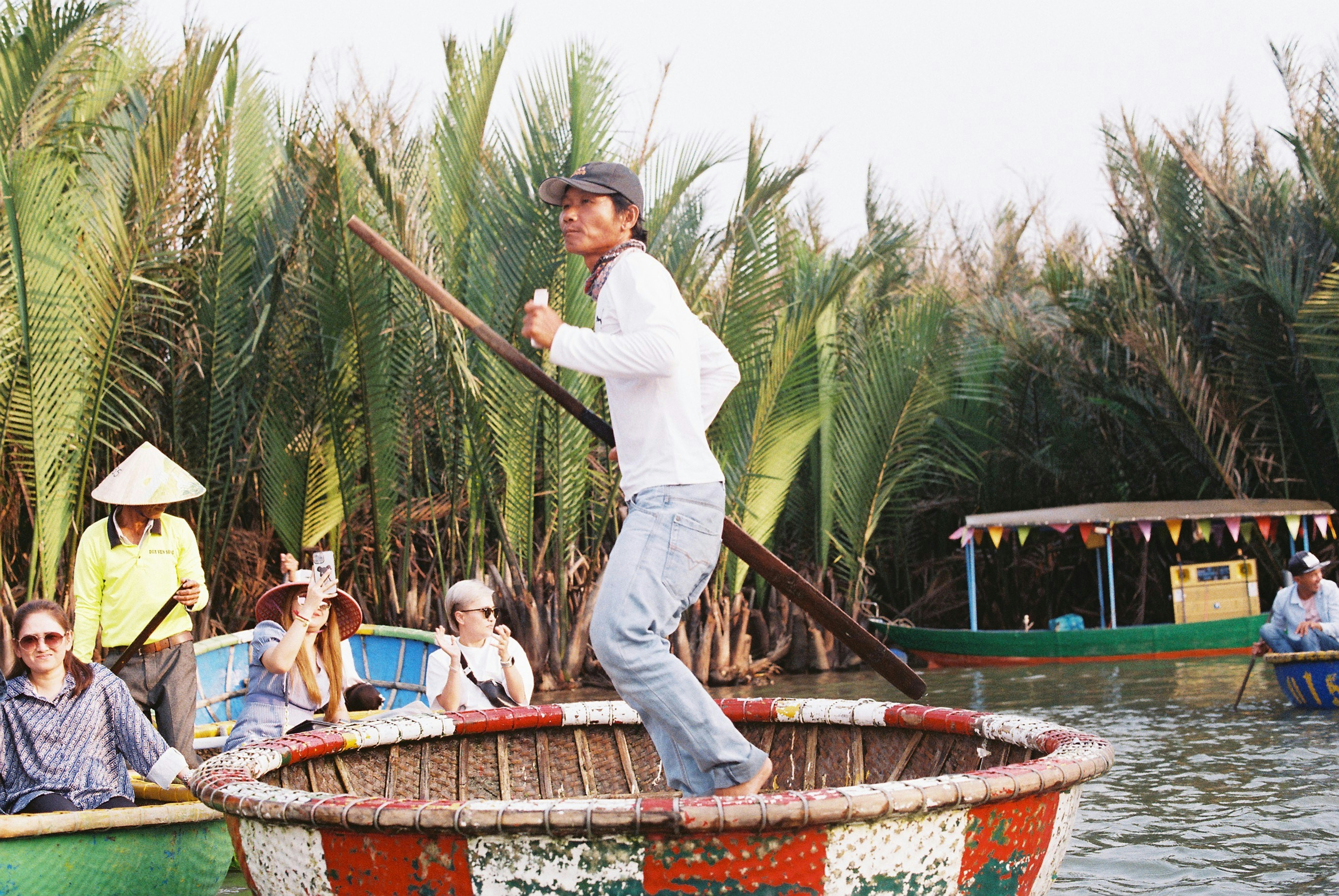A man standing in a round basket boat on a river in Vietnam