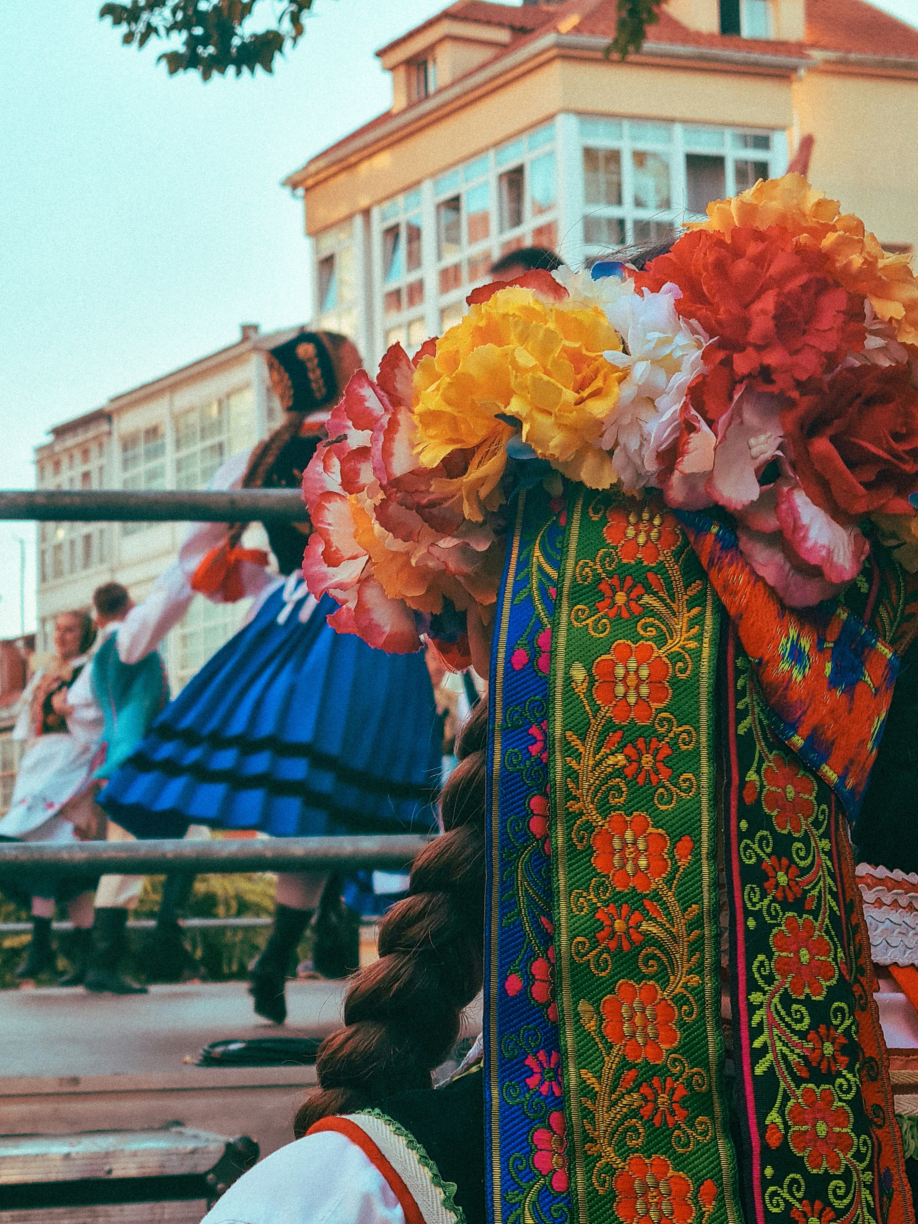 A person wearing a floral headpiece and braided hair with dancers in the background