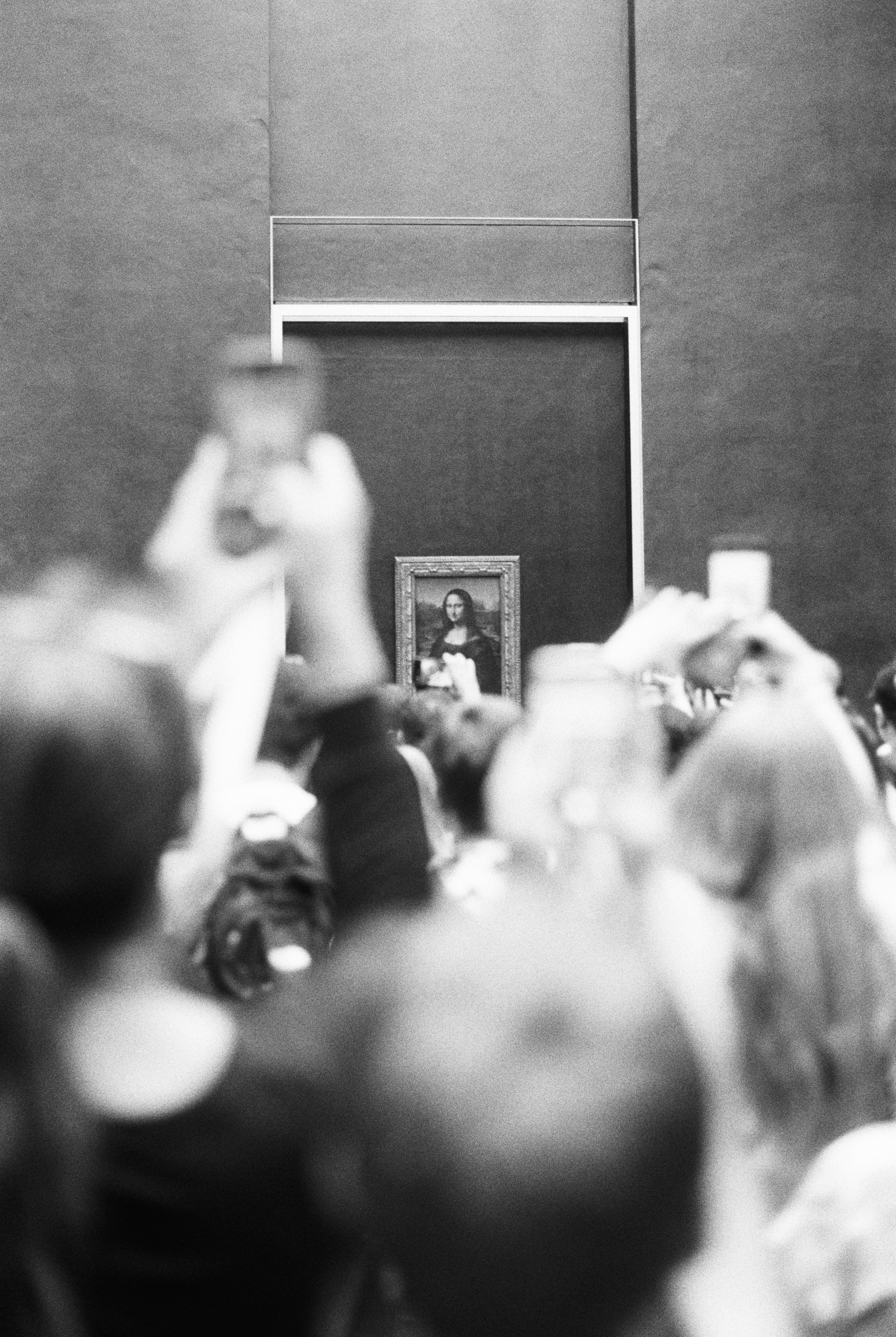 A crowd of people holding up phones to photograph the Mona Lisa in Paris