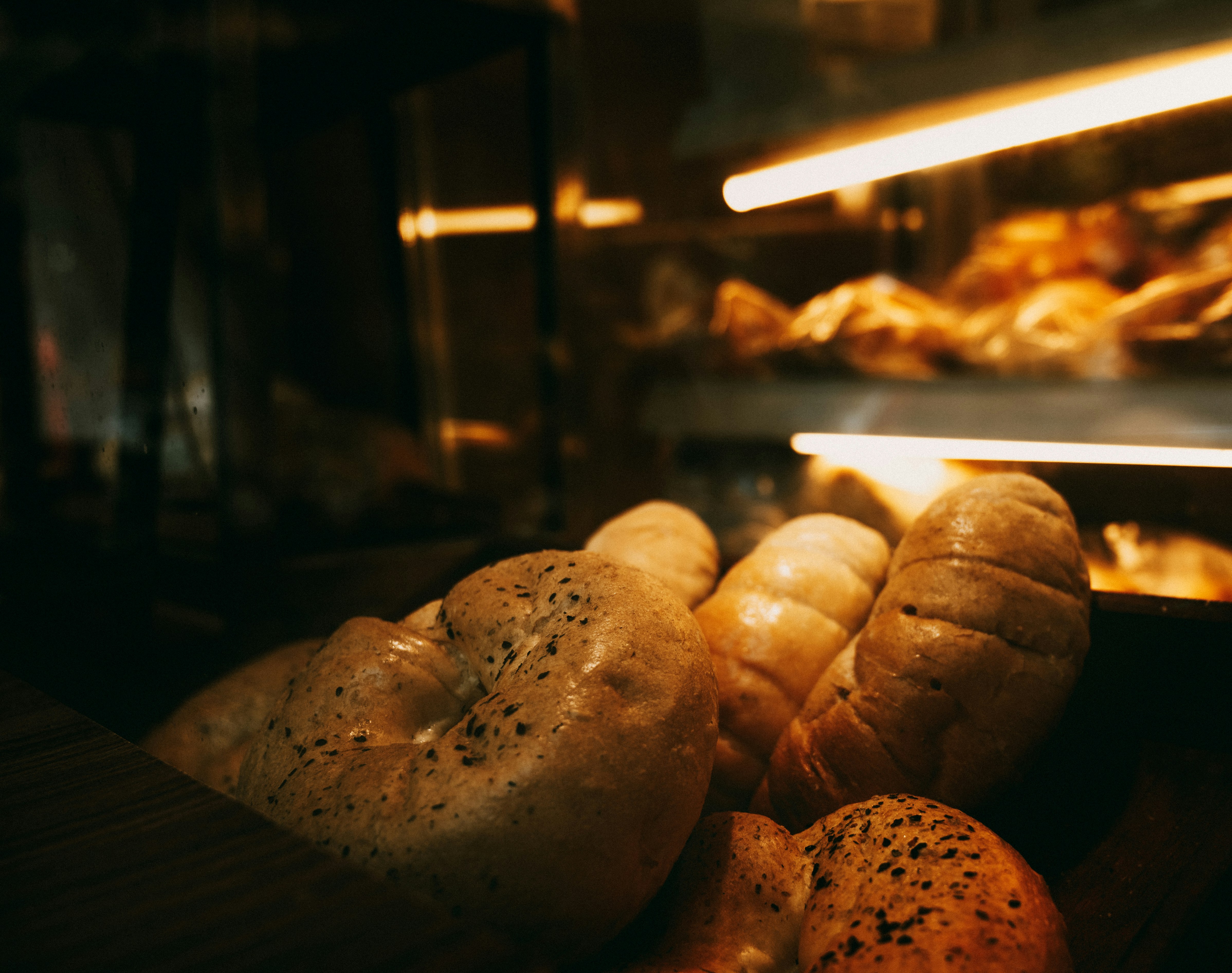 Freshly baked bagels and loaves of bread in a warm, dimly lit bakery display