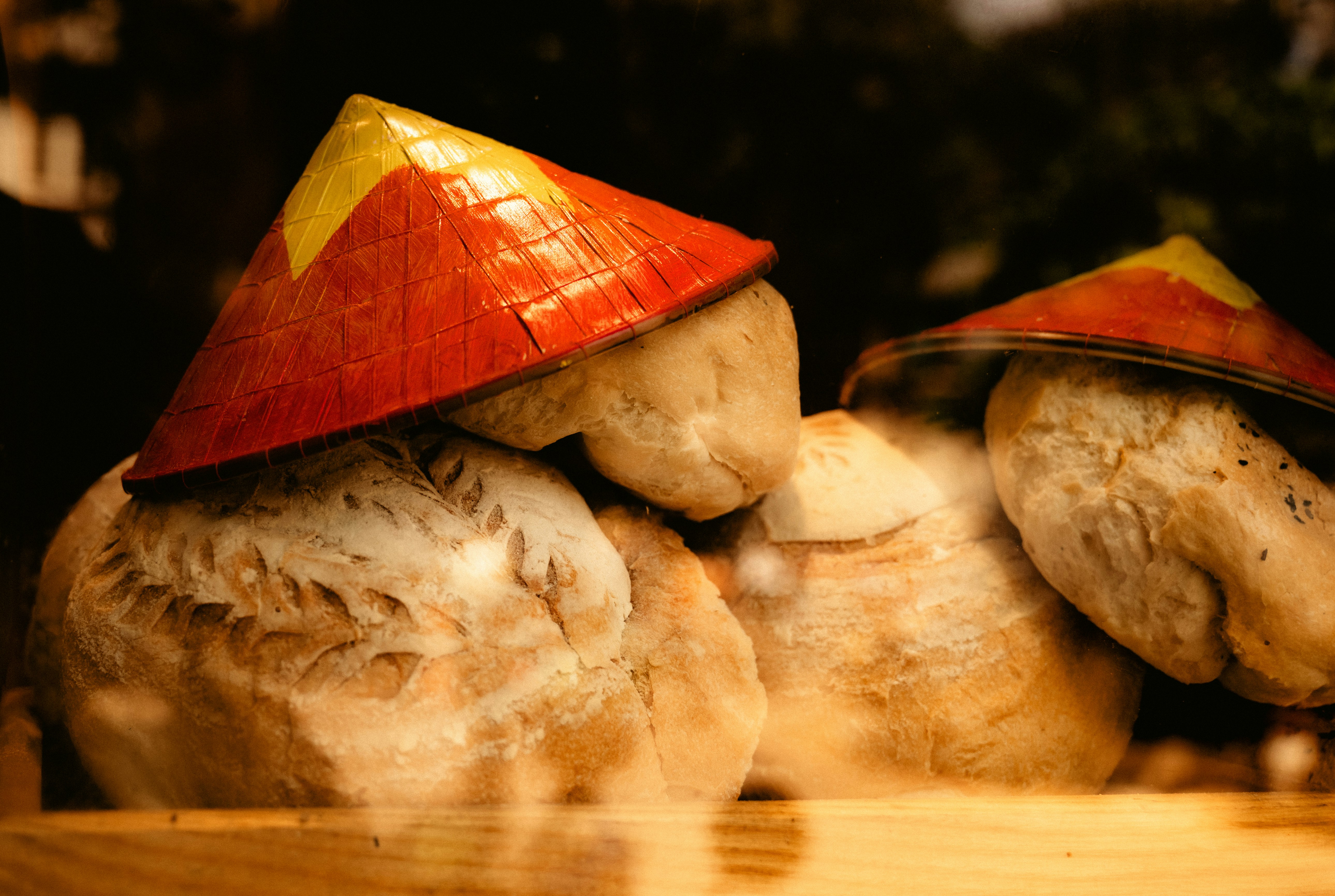 Two round loaves of bread topped with red and yellow conical hats