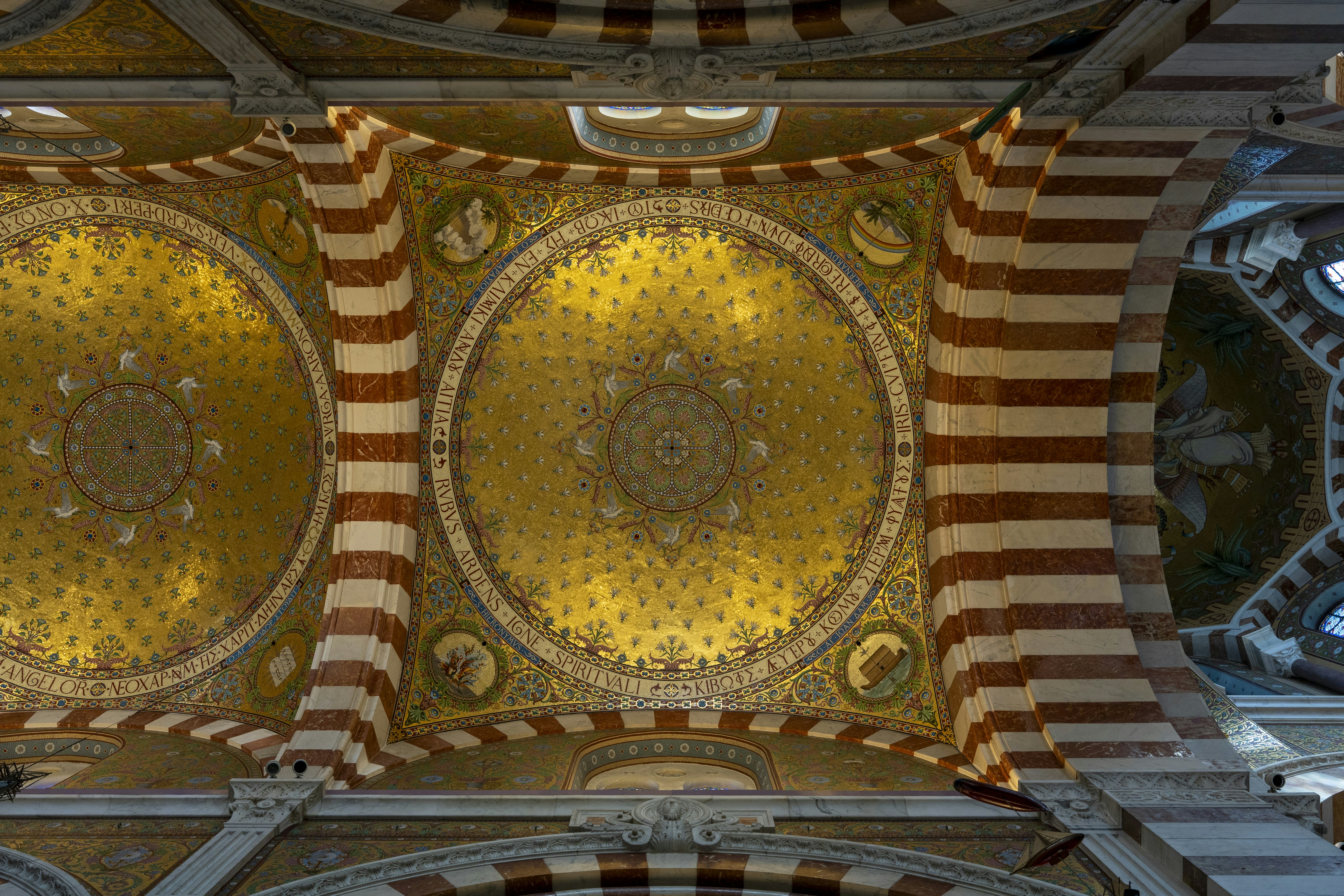 Gold mosaic domes with red and white striped arches in a cathedral ceiling