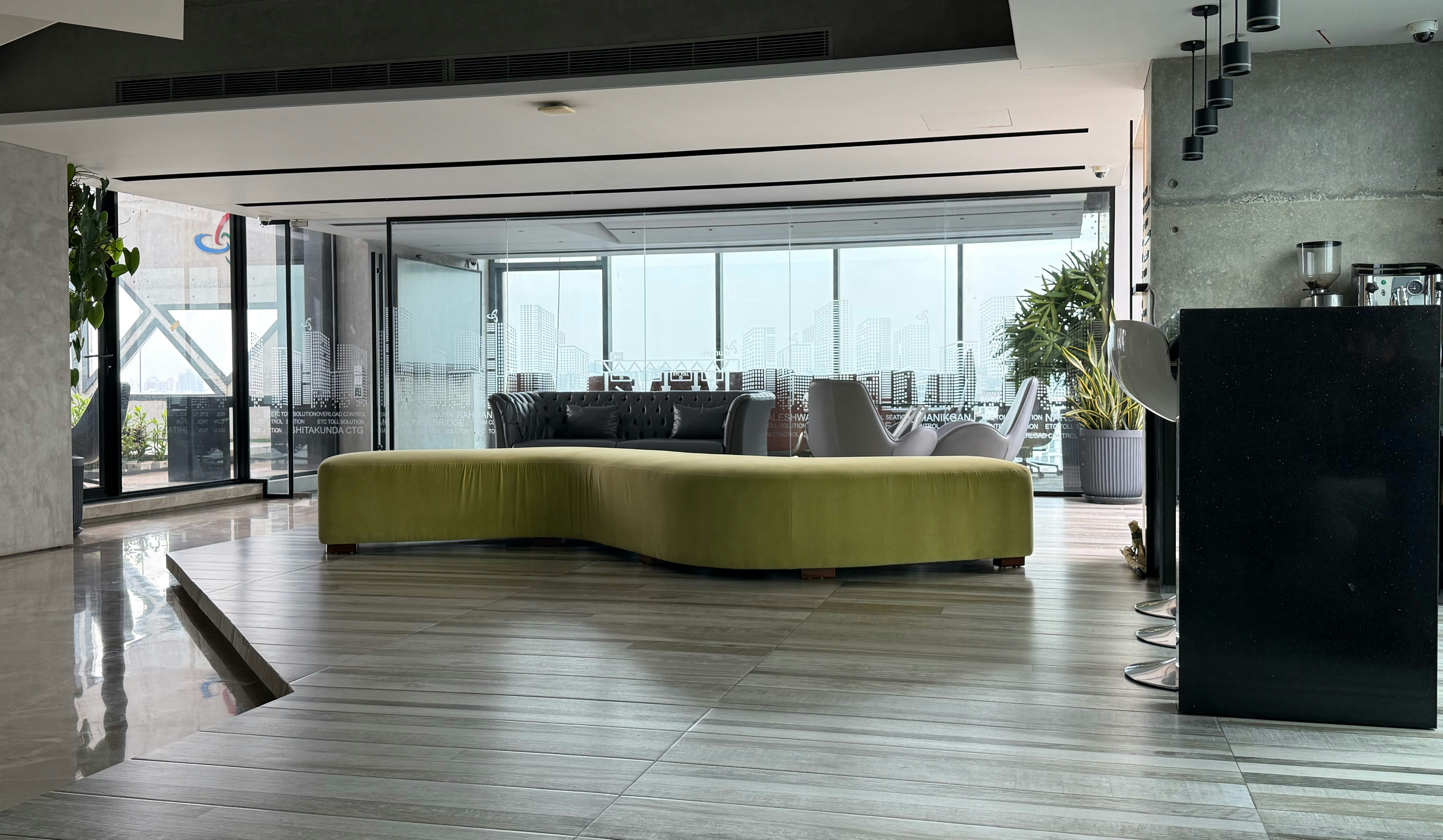 A curved lime green sofa in a modern office lounge with floor-to-ceiling windows