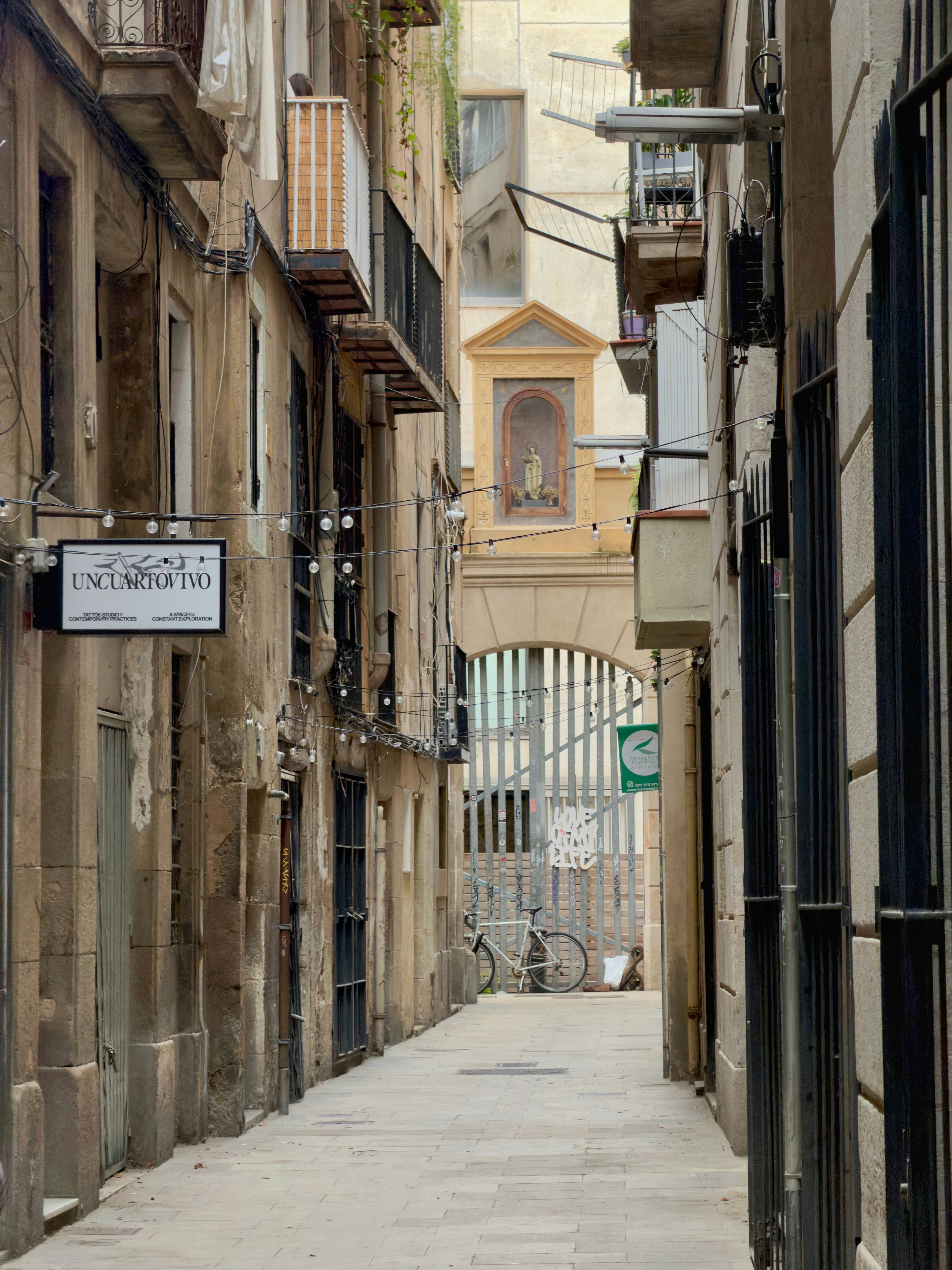 A narrow stone alleyway with a bicycle and a small shrine in the distance
