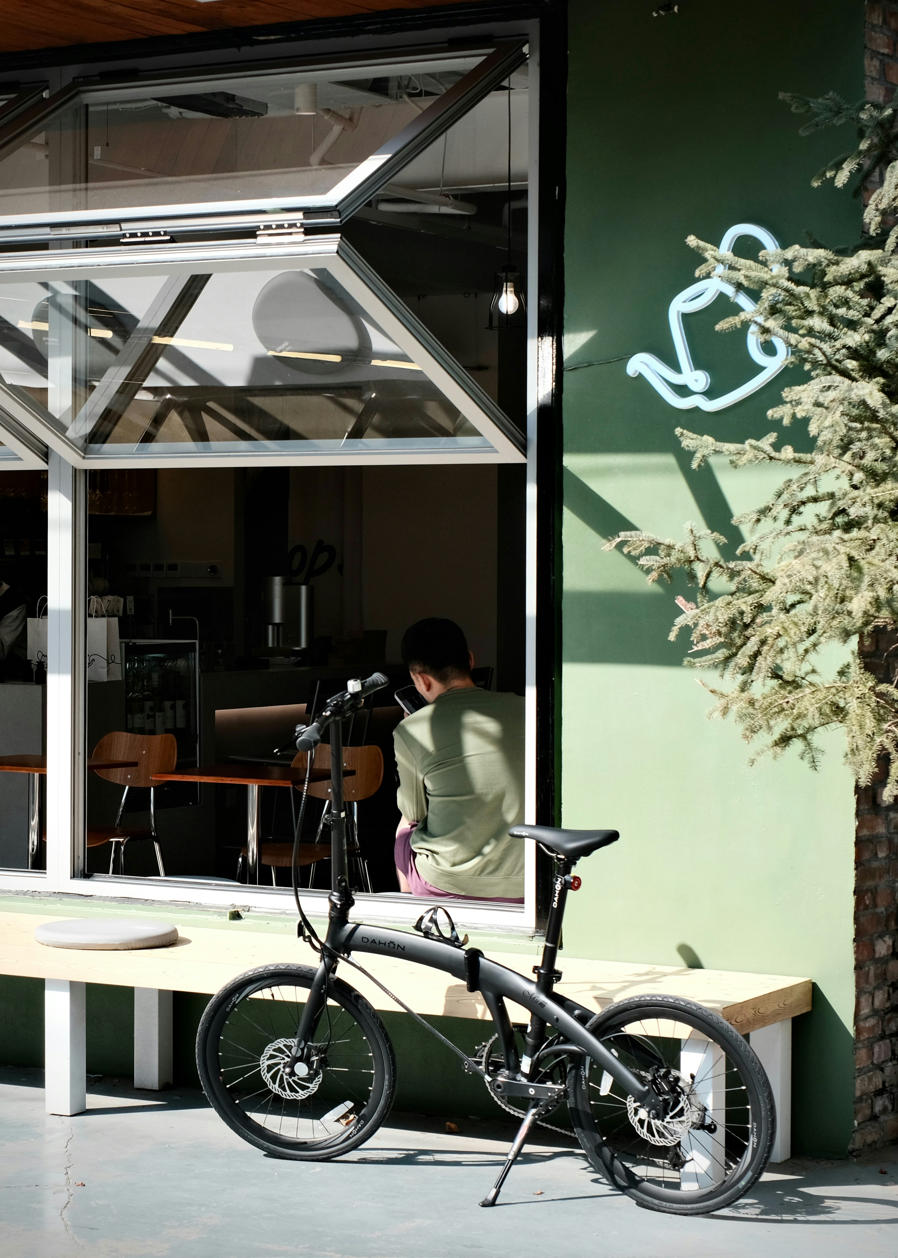 A person sitting in a cafe window beside a black folding bicycle
