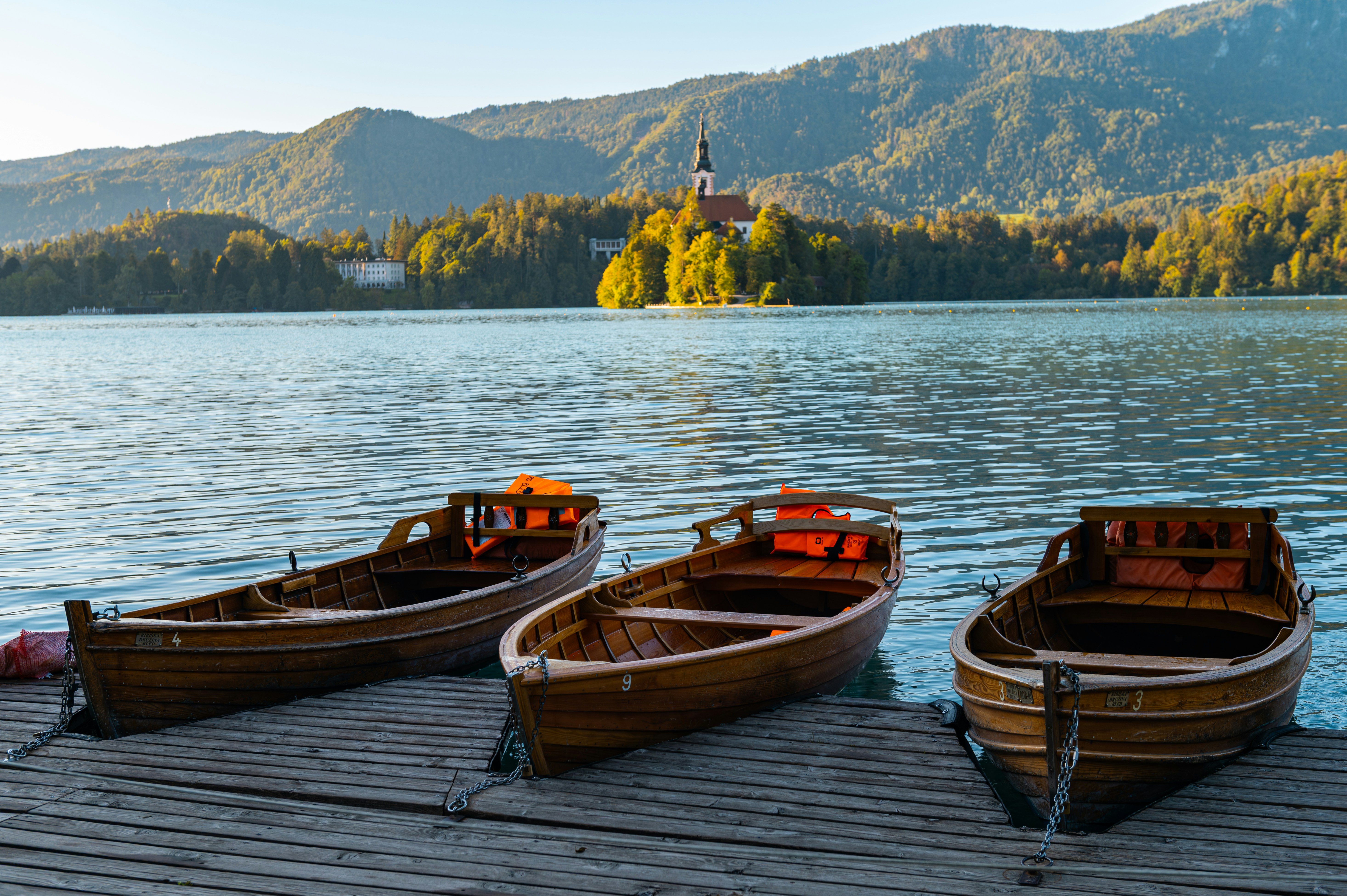 Three wooden rowboats moored at a wooden dock on Lake Bled in Slovenia