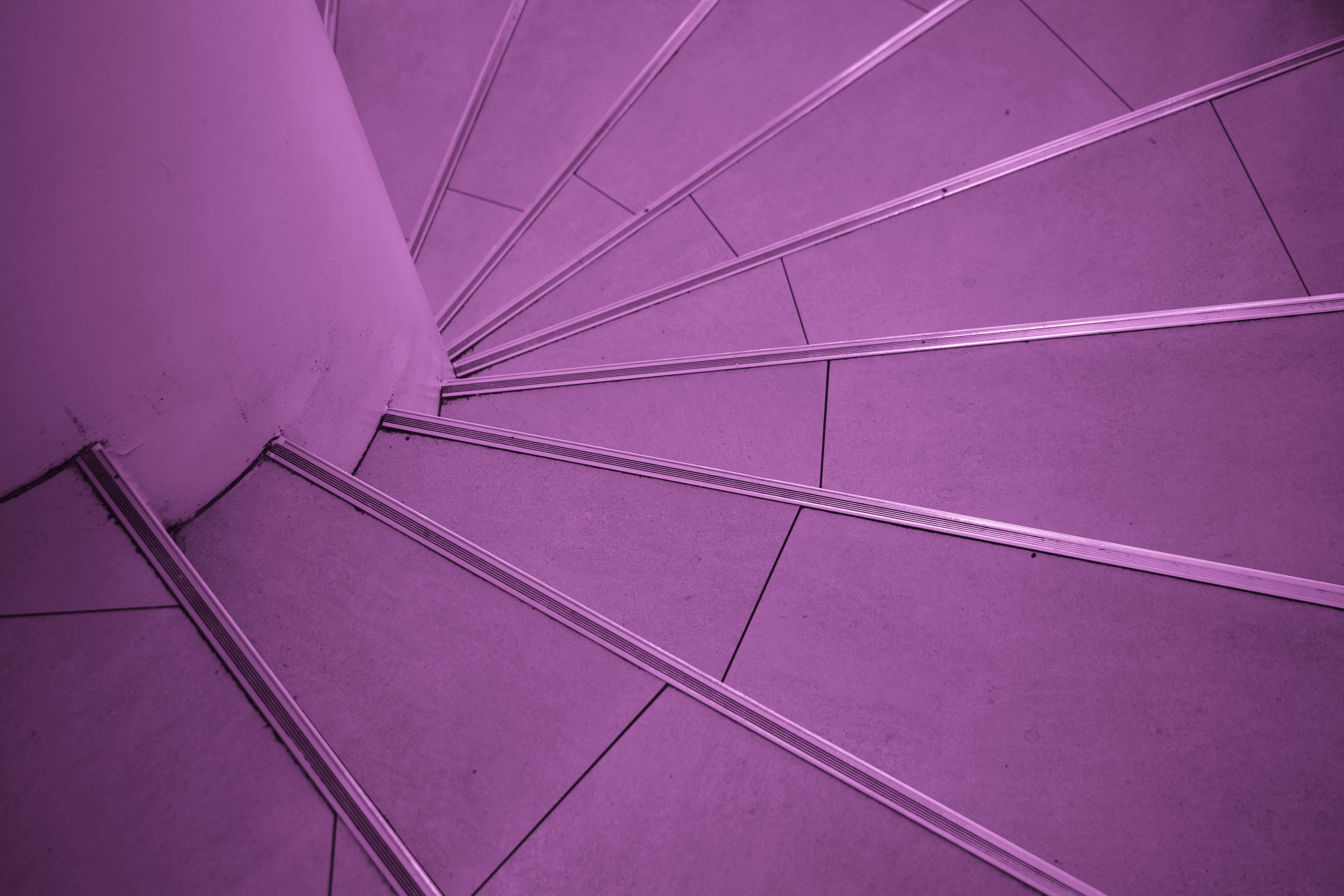 A spiral staircase with purple tiled steps and metallic edges