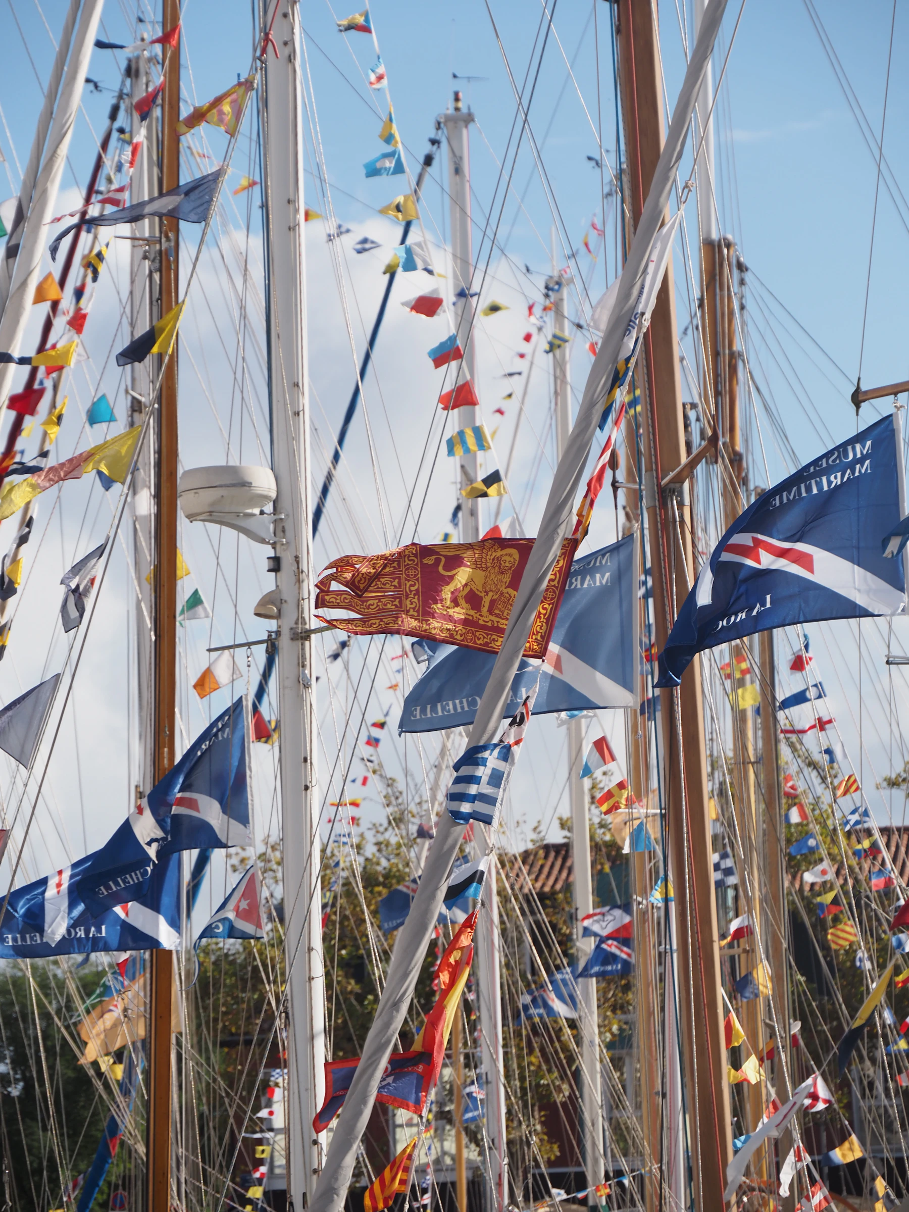The masts of moored sailing ships hung with strings of signal flags and pennants