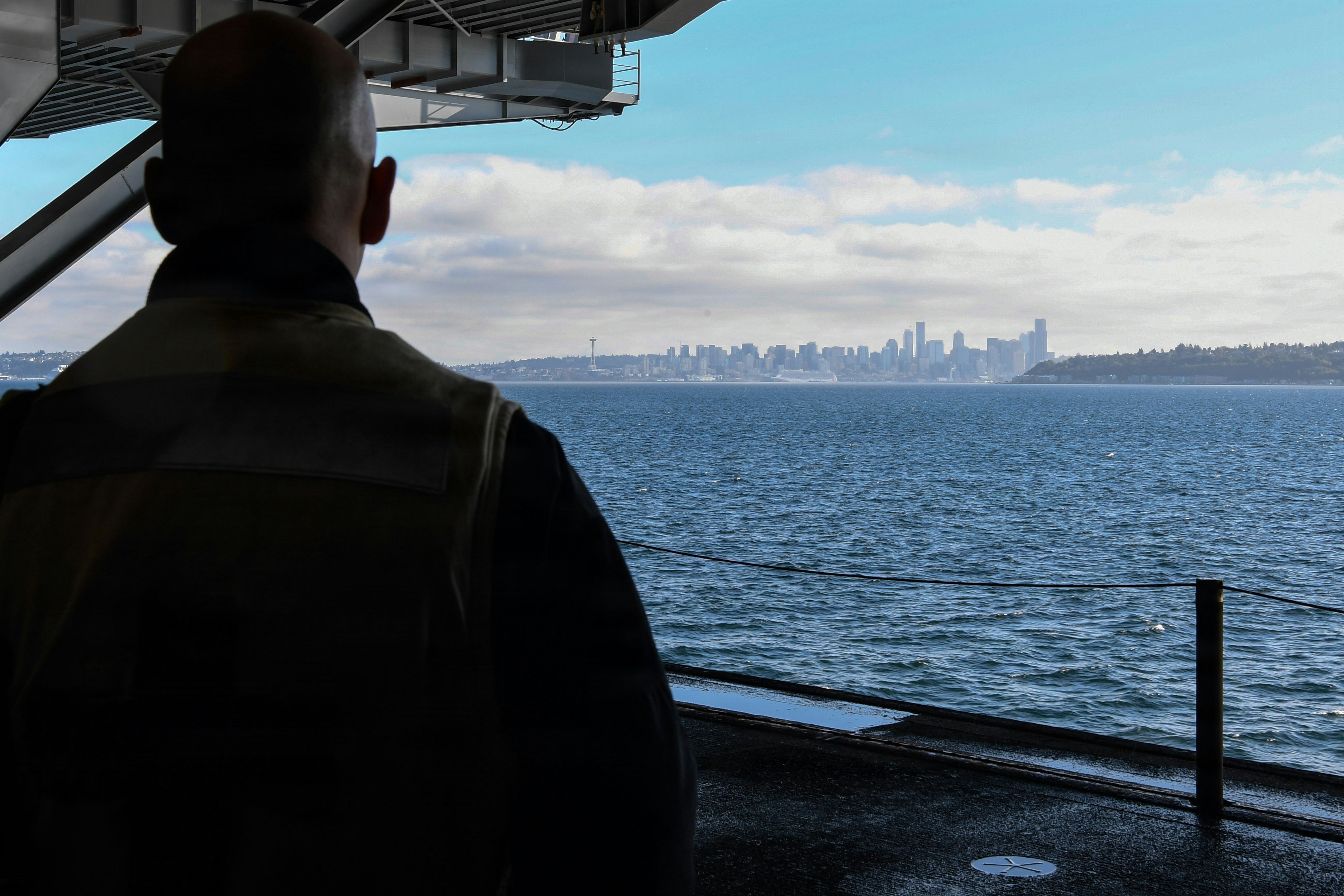 A person in silhouette looking toward the Seattle skyline across the water