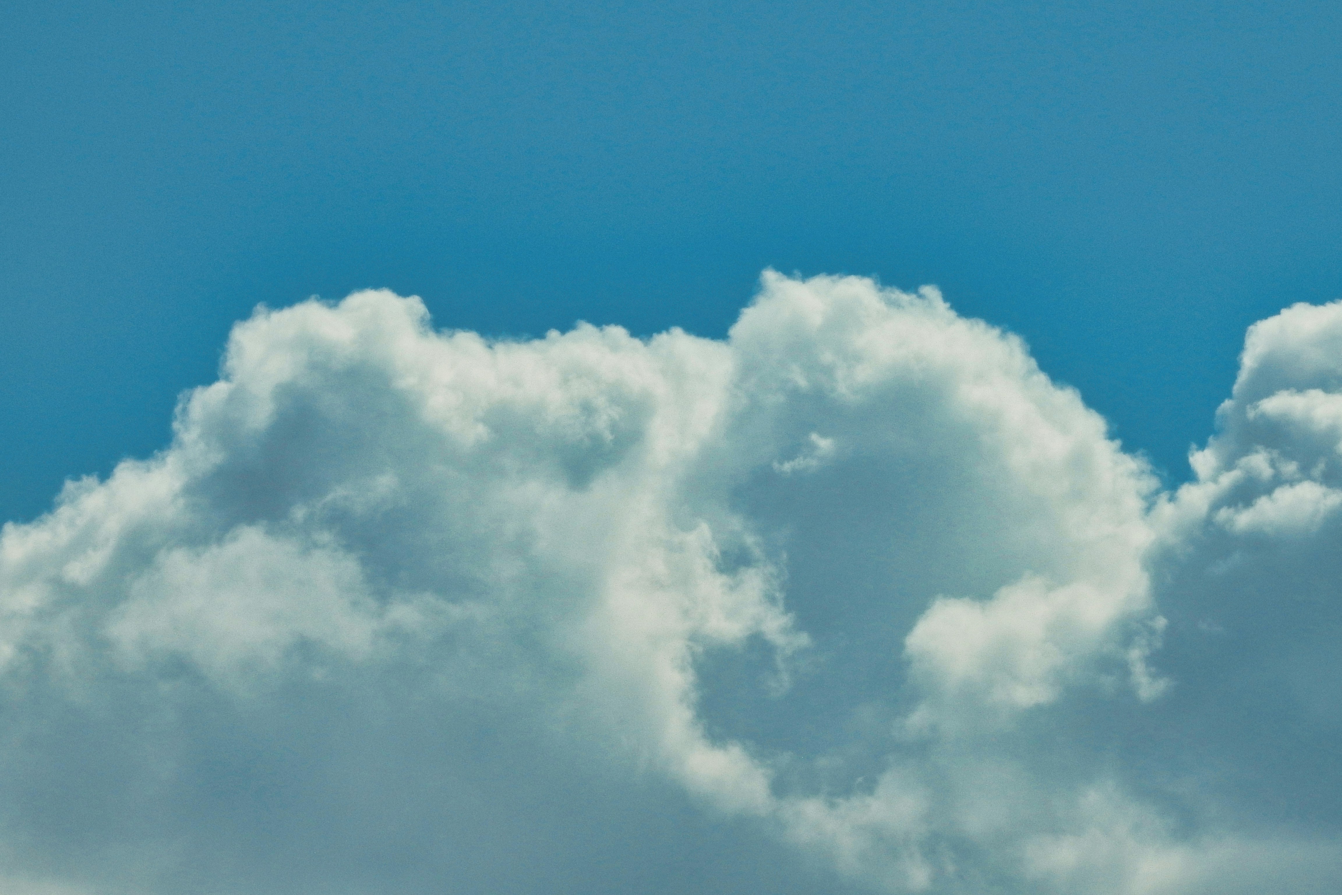 A fluffy white cumulus cloud against a clear blue sky