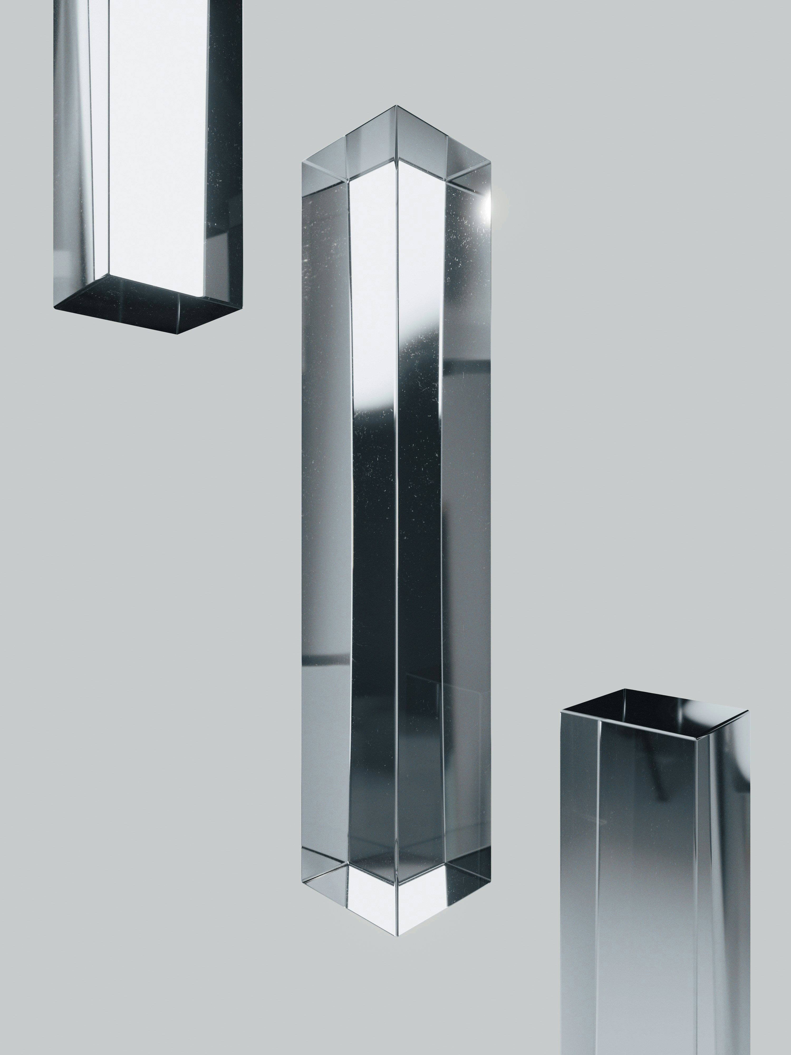 Three reflective glass rectangular prisms floating against a plain light grey background