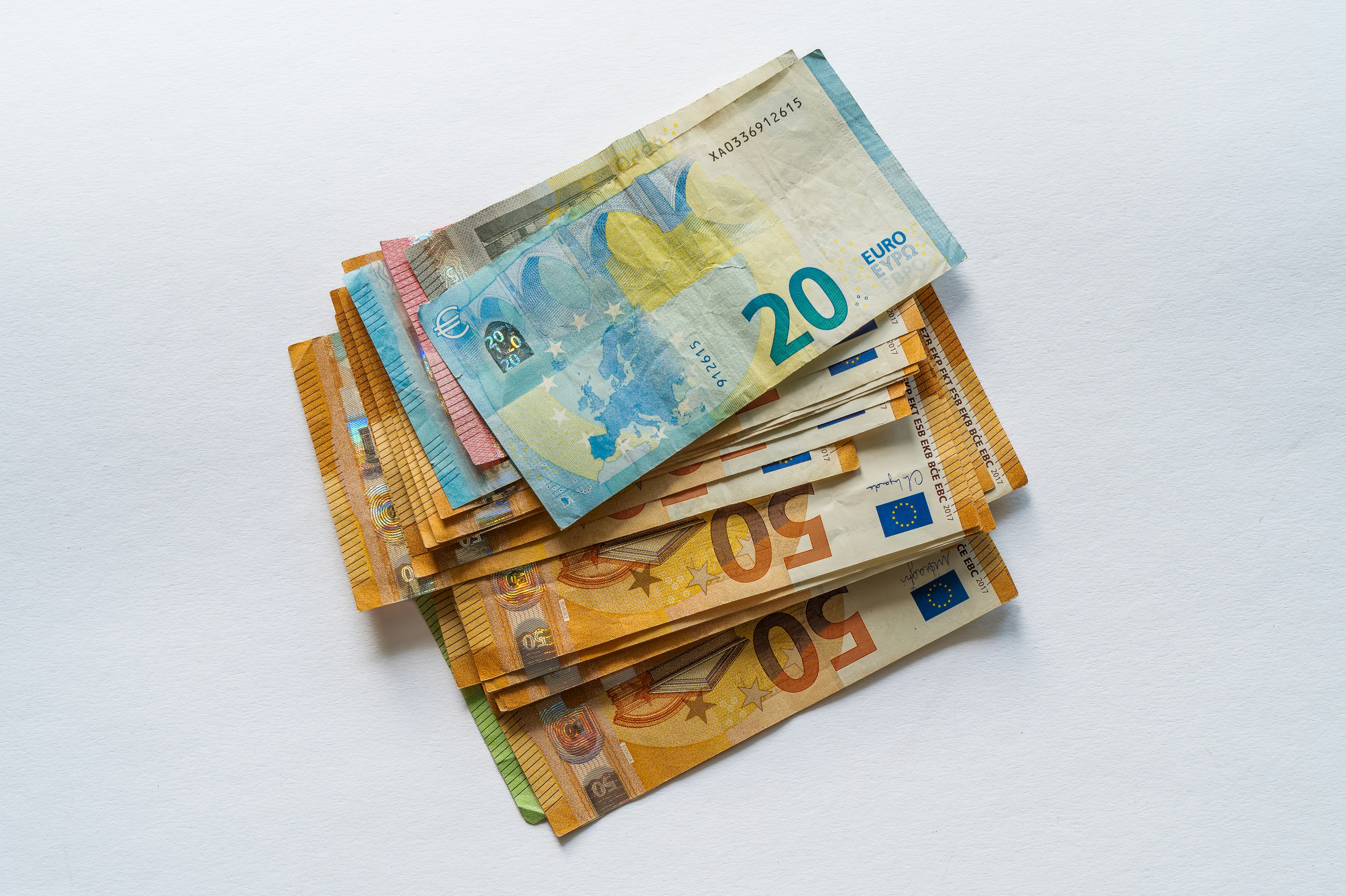 A stack of twenty and fifty euro banknotes on a white surface