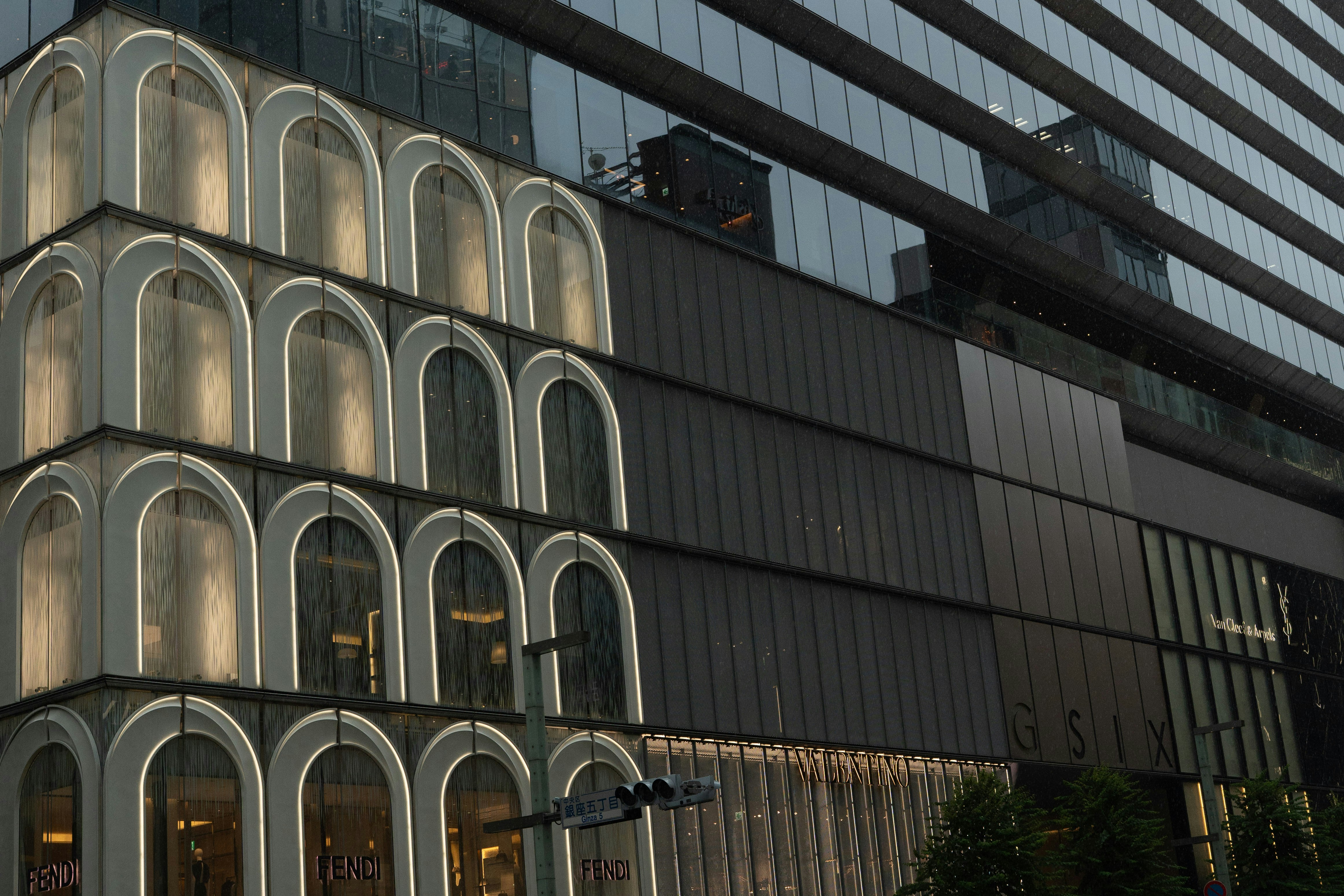 東京銀座の現代的な建物ファサード、照明付きのアーチ窓と暗いガラスパネル