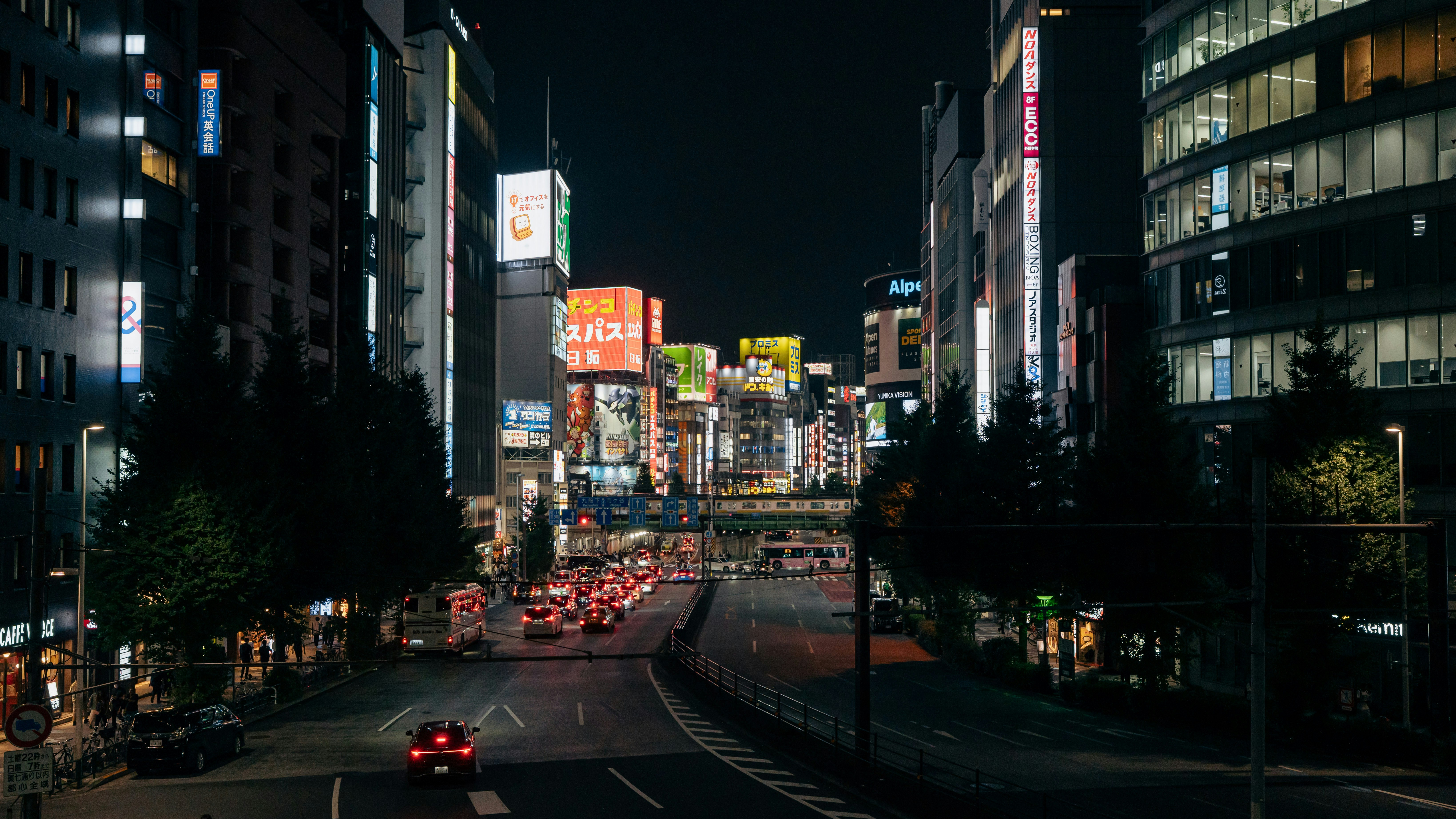 東京の夜の街の通りを走る車たちの姿は、ネオンサインが並ぶ場所で並んでいる