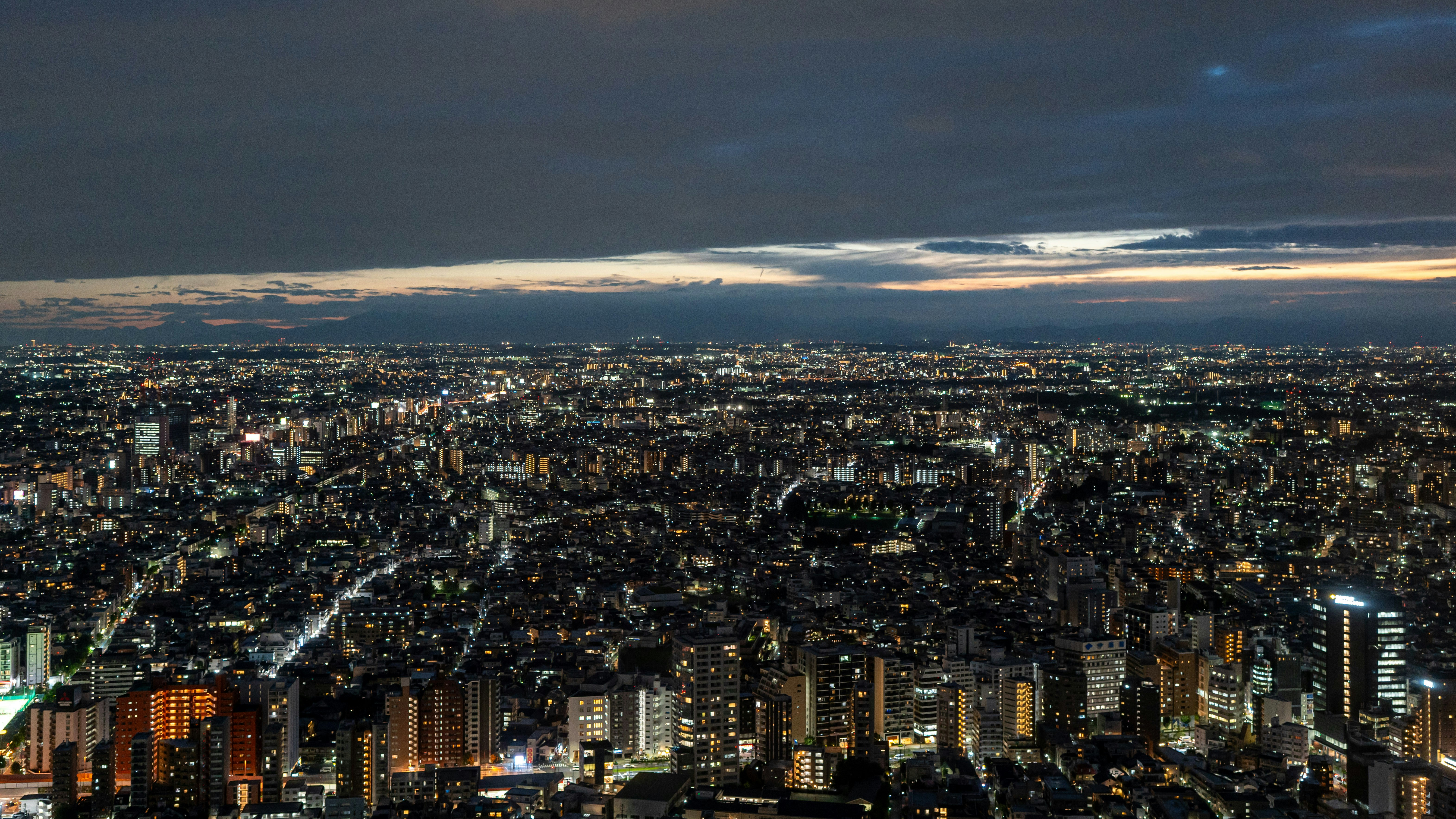 暗く曇った空の下、夜の広大な都市の空からの空撮